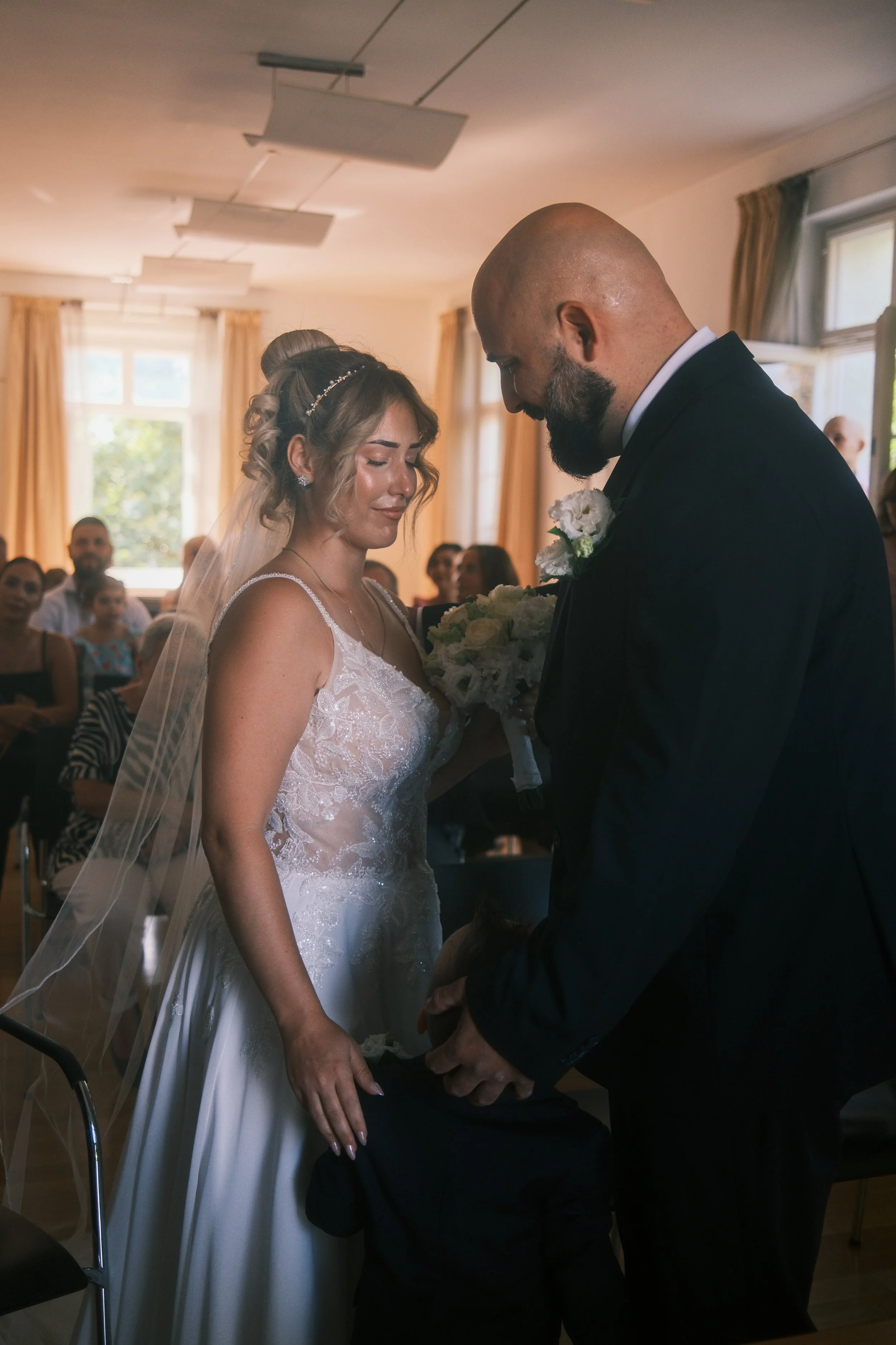 Brautpaar steht eng beieinander während der Trauung, Gäste im Hintergrund, Hochzeit in Leipzig