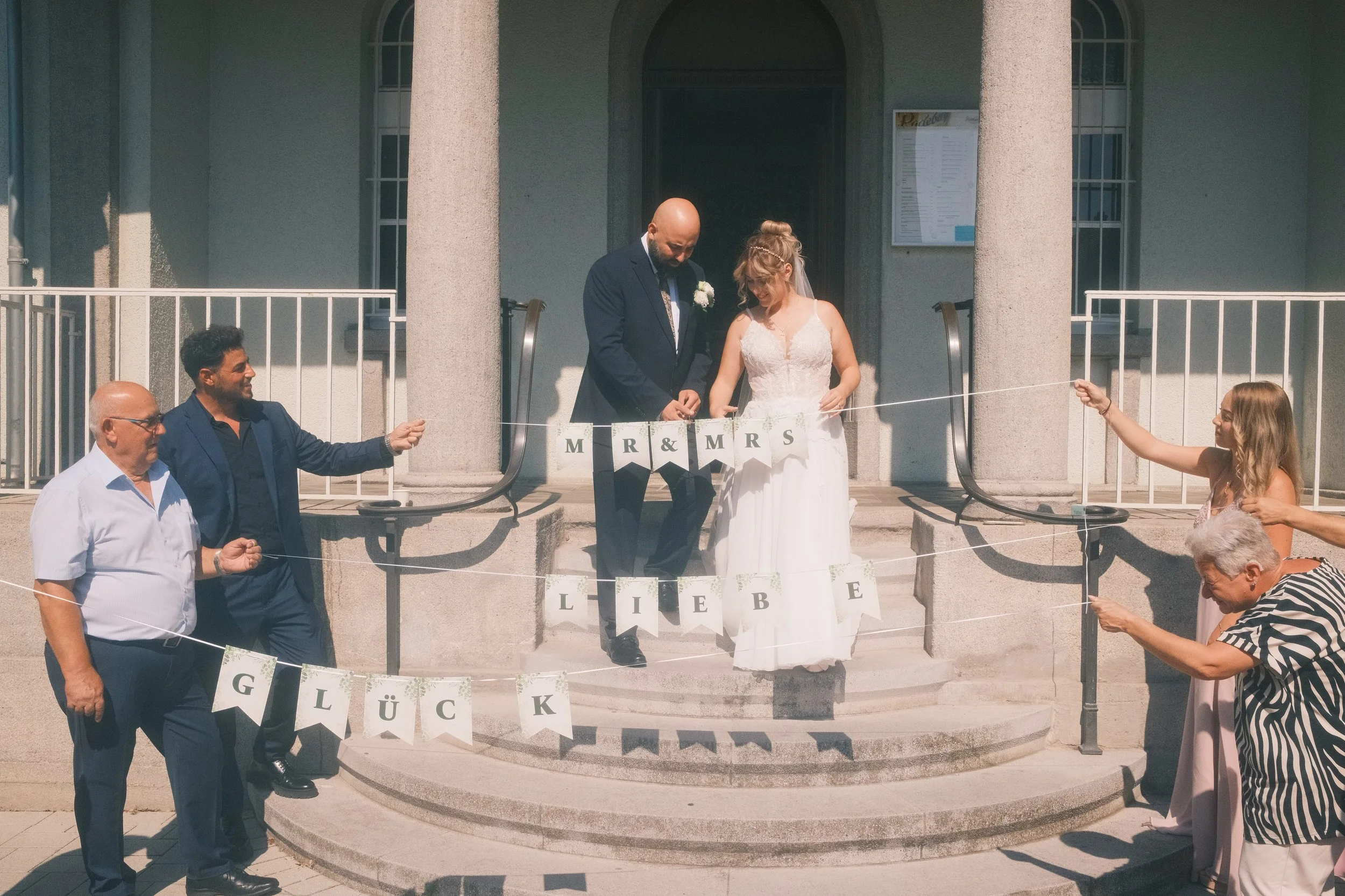 Brautpaar geht durch eine "Mr & Mrs – Liebe – Glück"-Wimpelkette vor dem Standesamt Leipzig