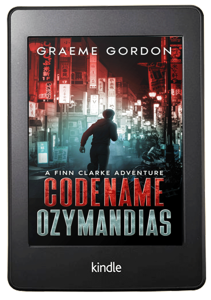 A Kindle e-reader displaying the cover of the book "Codename Ozymandias" by Graeme Gordon, featuring a teen running in a neon-lit city street at night with Asian signs and buildings.