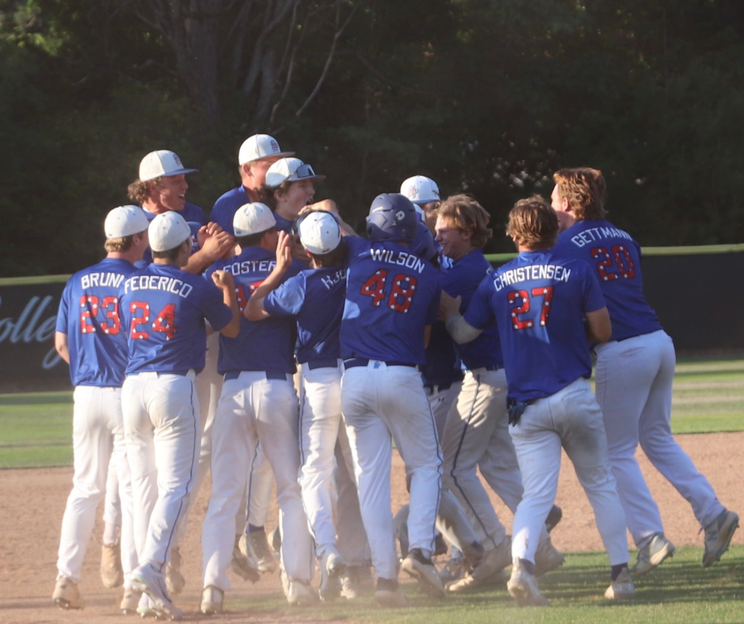 A group of baseball players wearing blue jerseys and white pants celebrating on the field.
