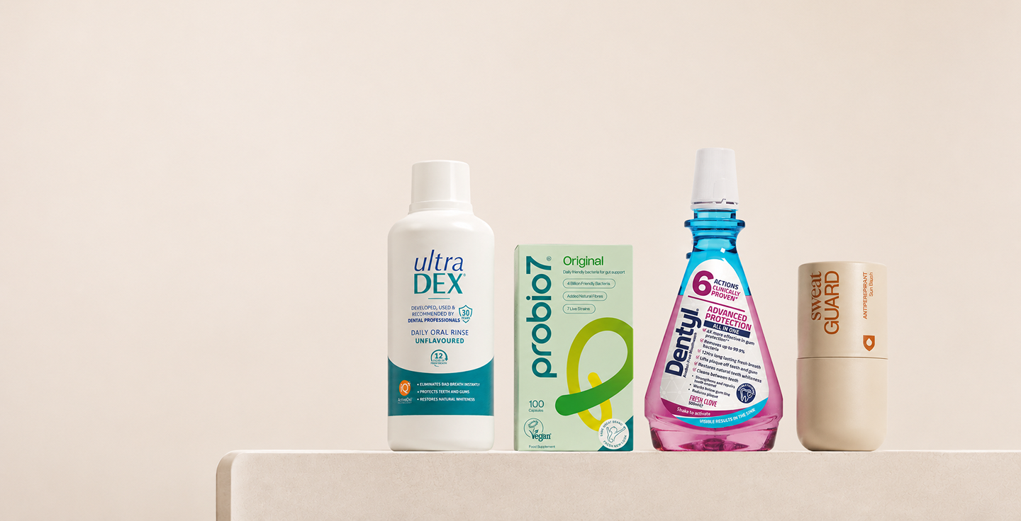 Personal care products including Ultra DEX daily oral rinse, probiotic supplement, Dentyal mouth spray, and Sweat Guard antiperspirant on a white surface.