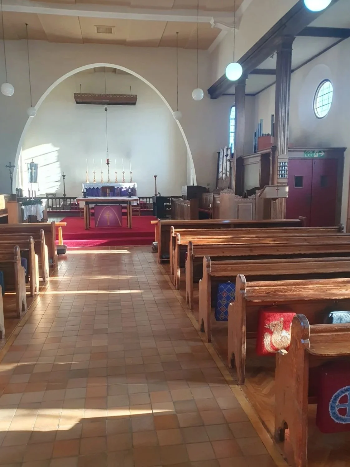 Interior of a church with wooden pews, altar, and religious decorations.
