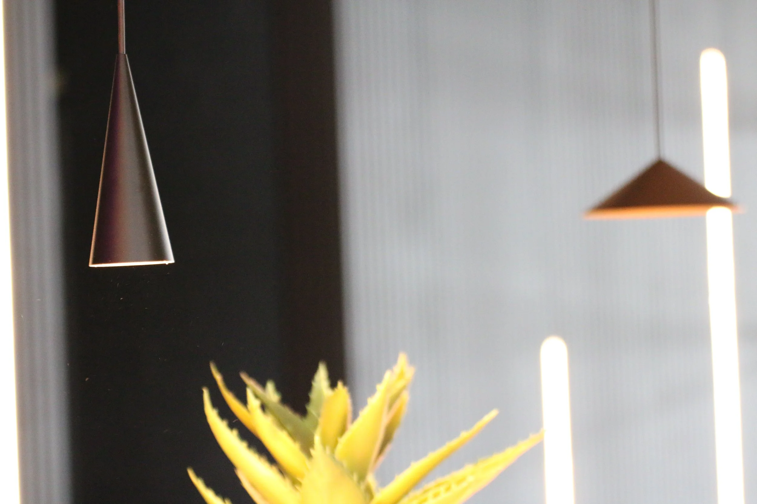 Eine gelbe Ananas im Vordergrund und moderne, hängende Lampen im Hintergrund.