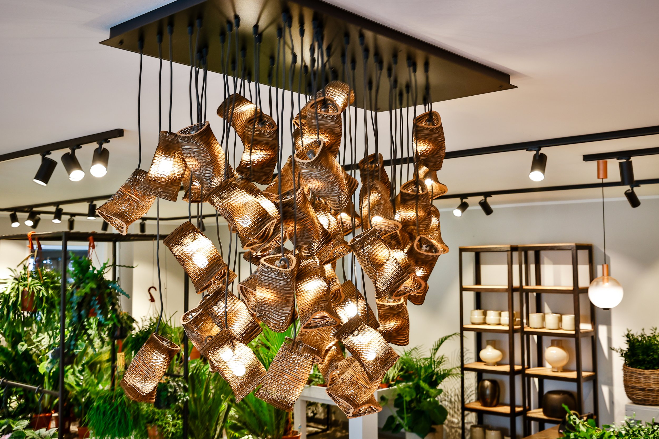 Moderne Hängeleuchte mit zahlreichen goldfarbenen, gewellten Metallabschirmungen, die um Lichtquellen herum angeordnet sind.