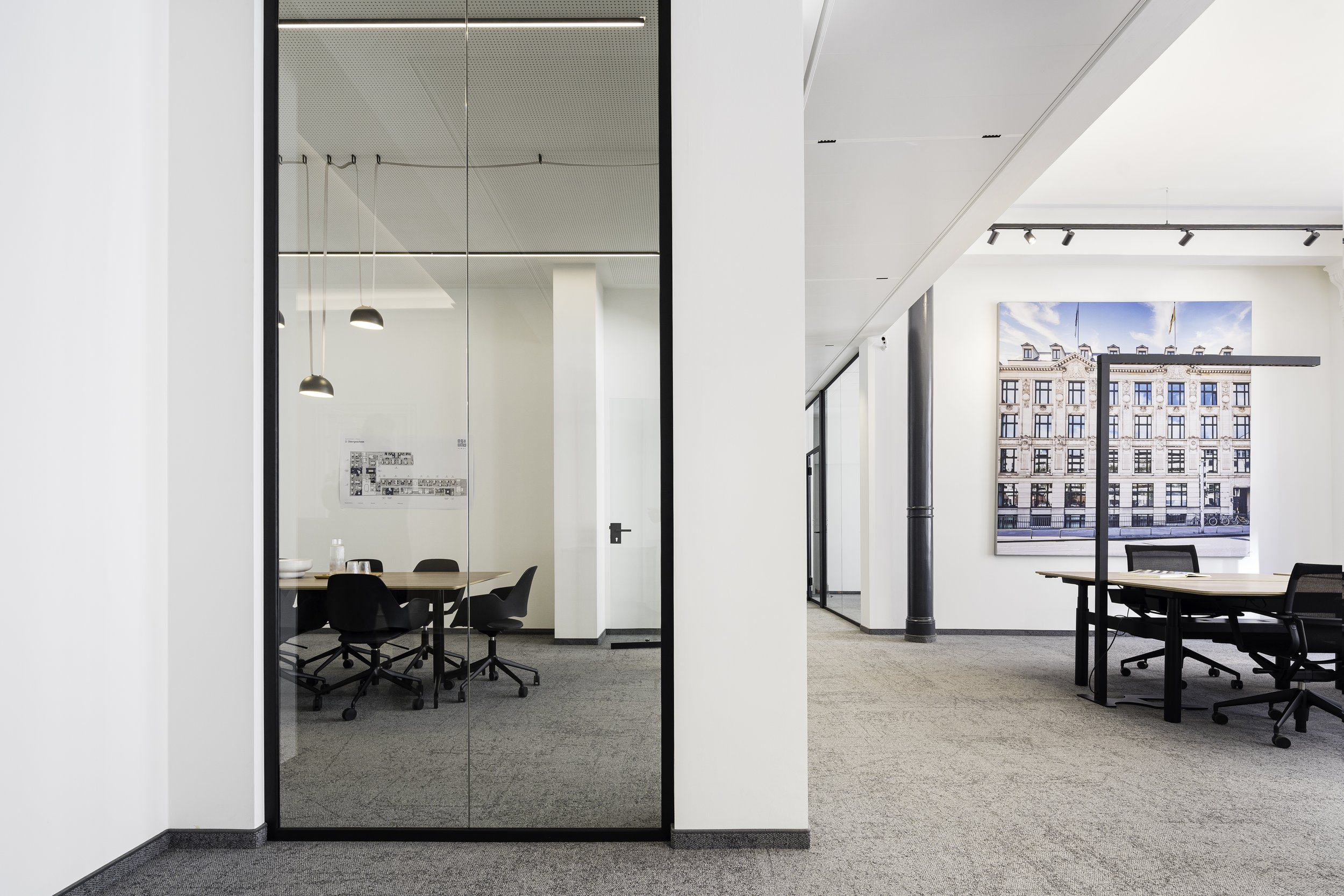 Moderne Büro mit großen Fenstern, Besprechungstisch, Stühlen und Stadtblick im Hintergrund.