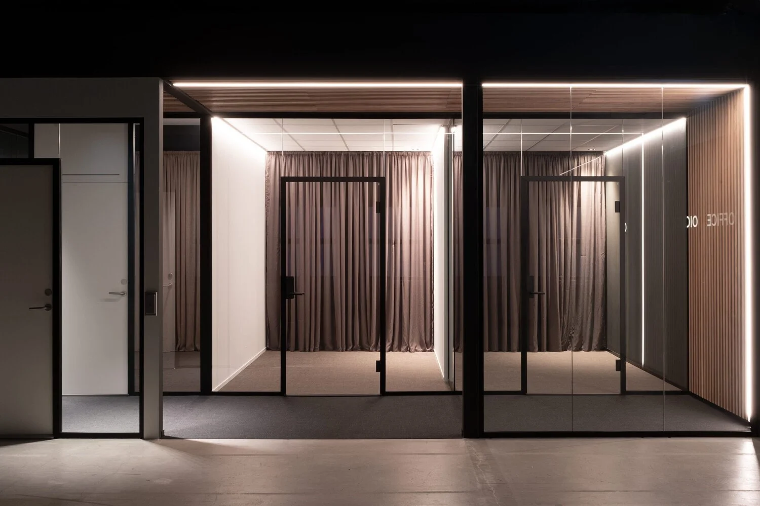 Interior of a modern office space with glass doors, curtains, and minimalistic design.