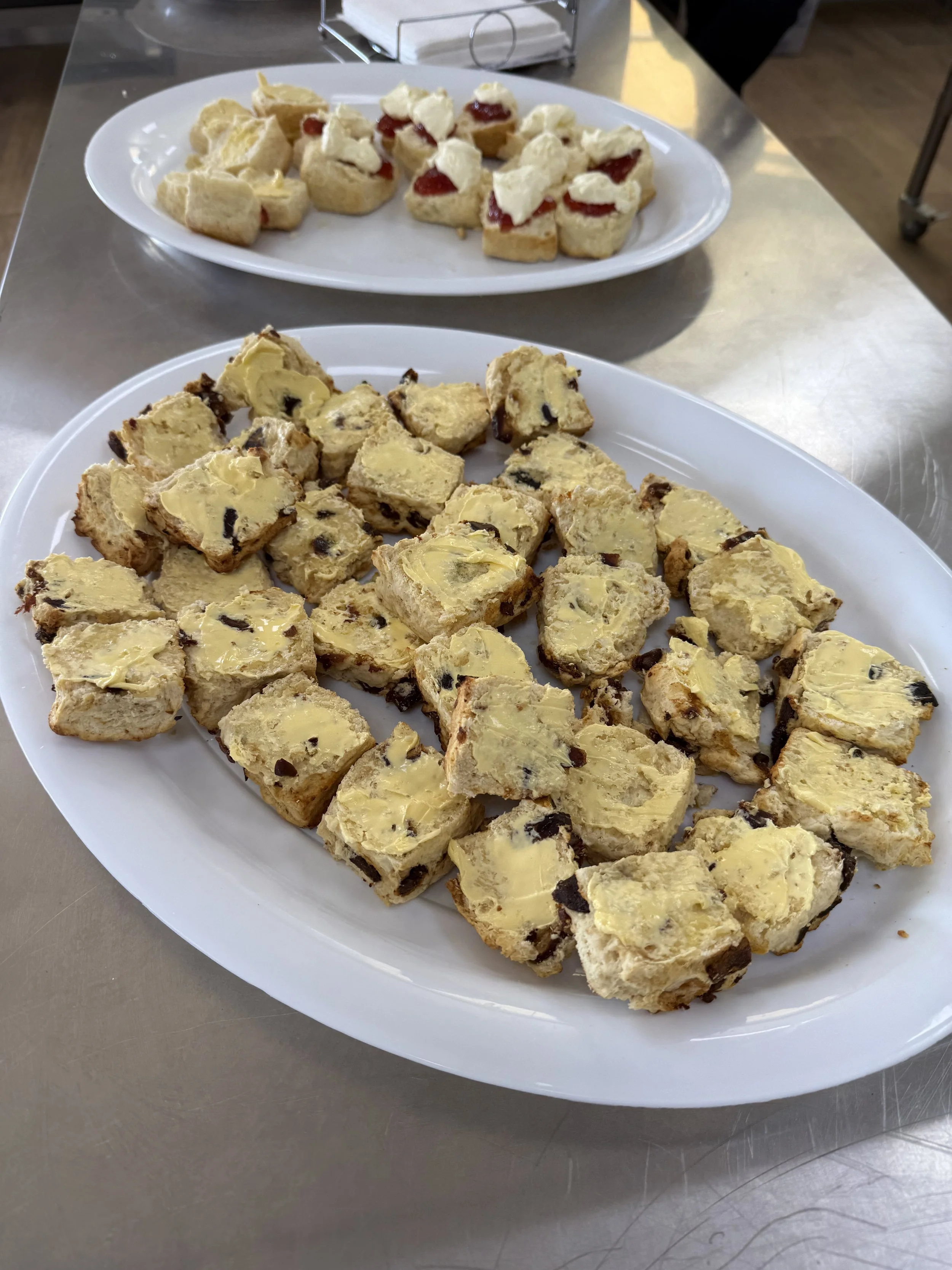Plates of fresh-made date scones and scones with jam and cream.
