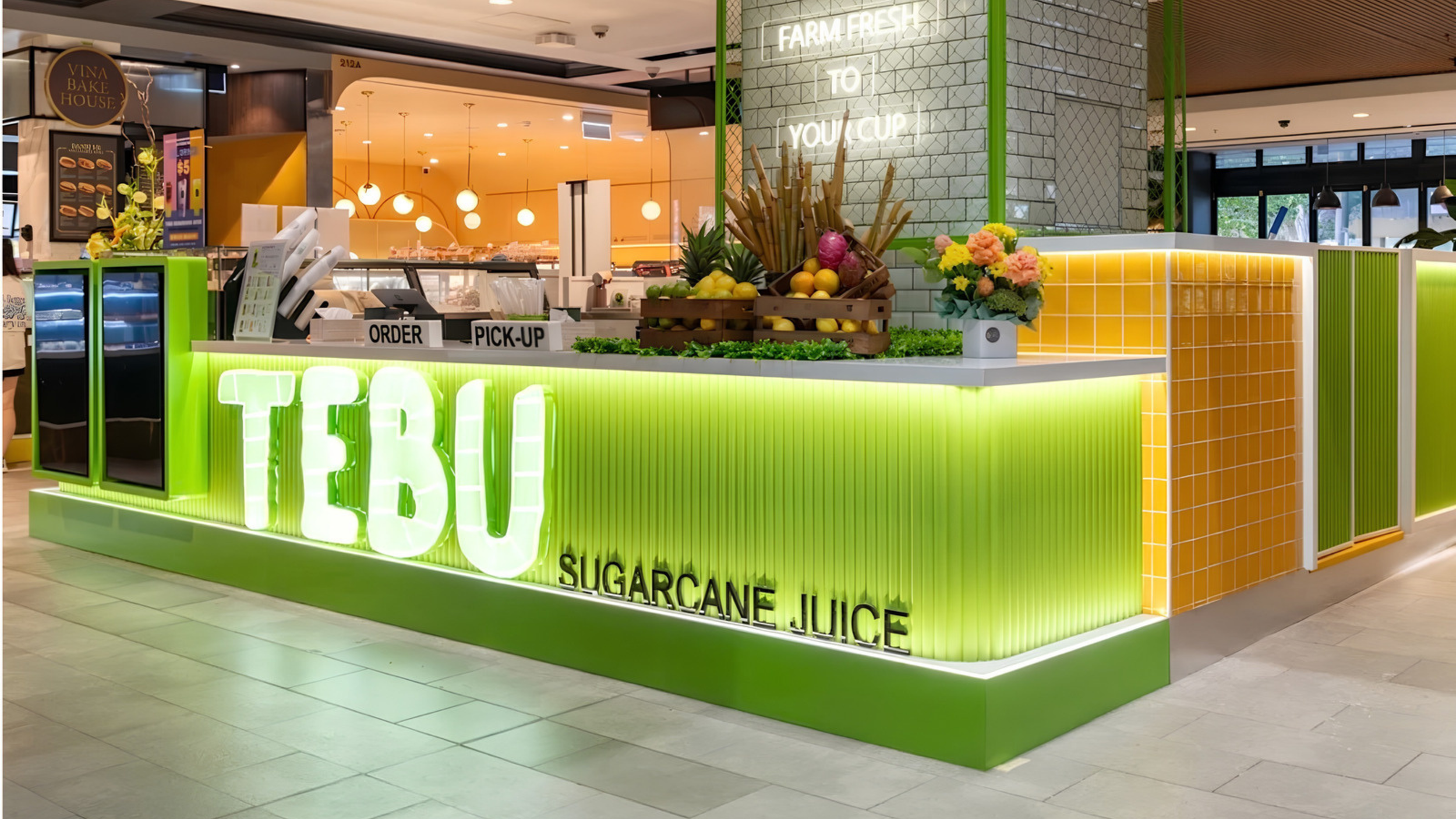 Tebu sugarcane juice kiosk with an illuminated green counter and fresh produce display
