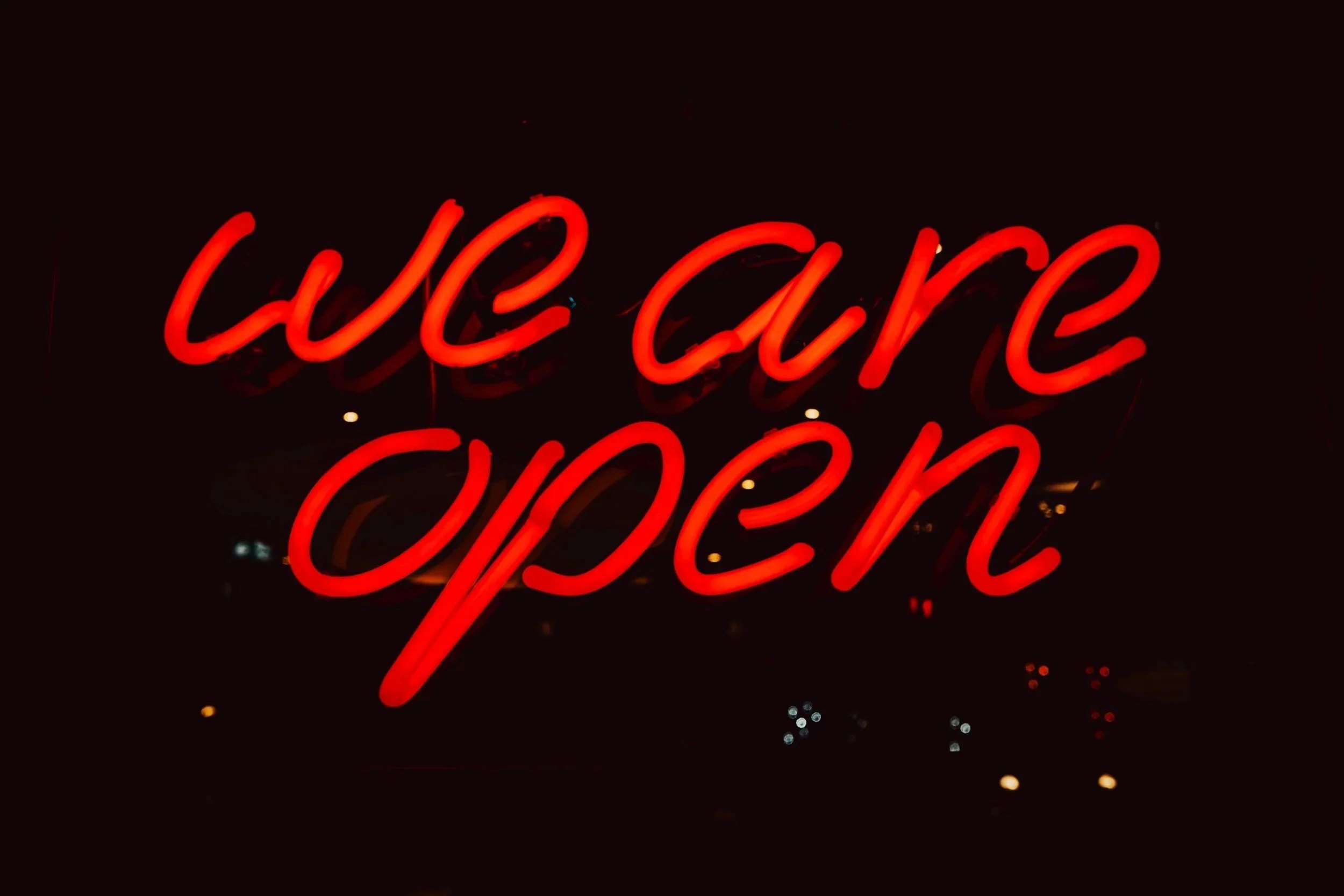 Red neon sign with the words 'Cafe Open' glowing in darkness.