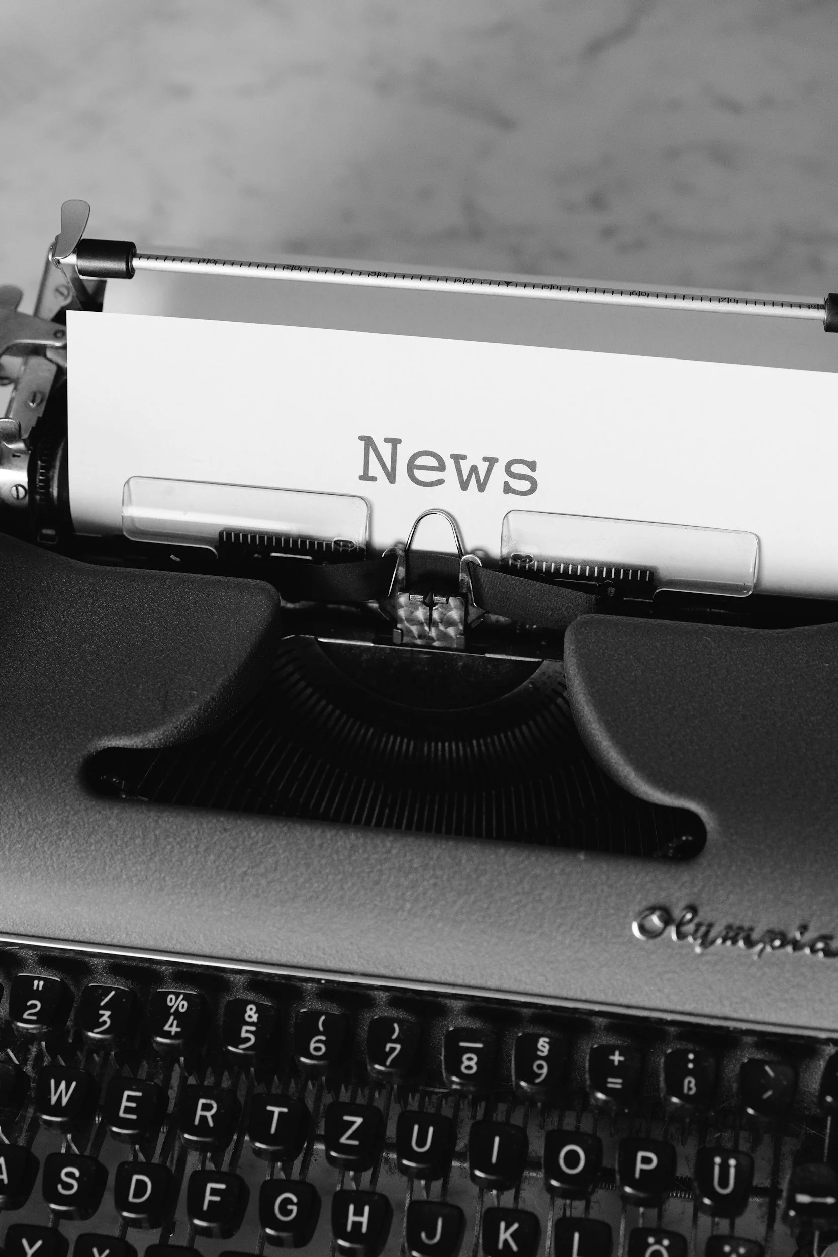 Eine alte Schreibmaschine mit einer weißen Papierrolle, auf der das Wort 'News' gedruckt ist.