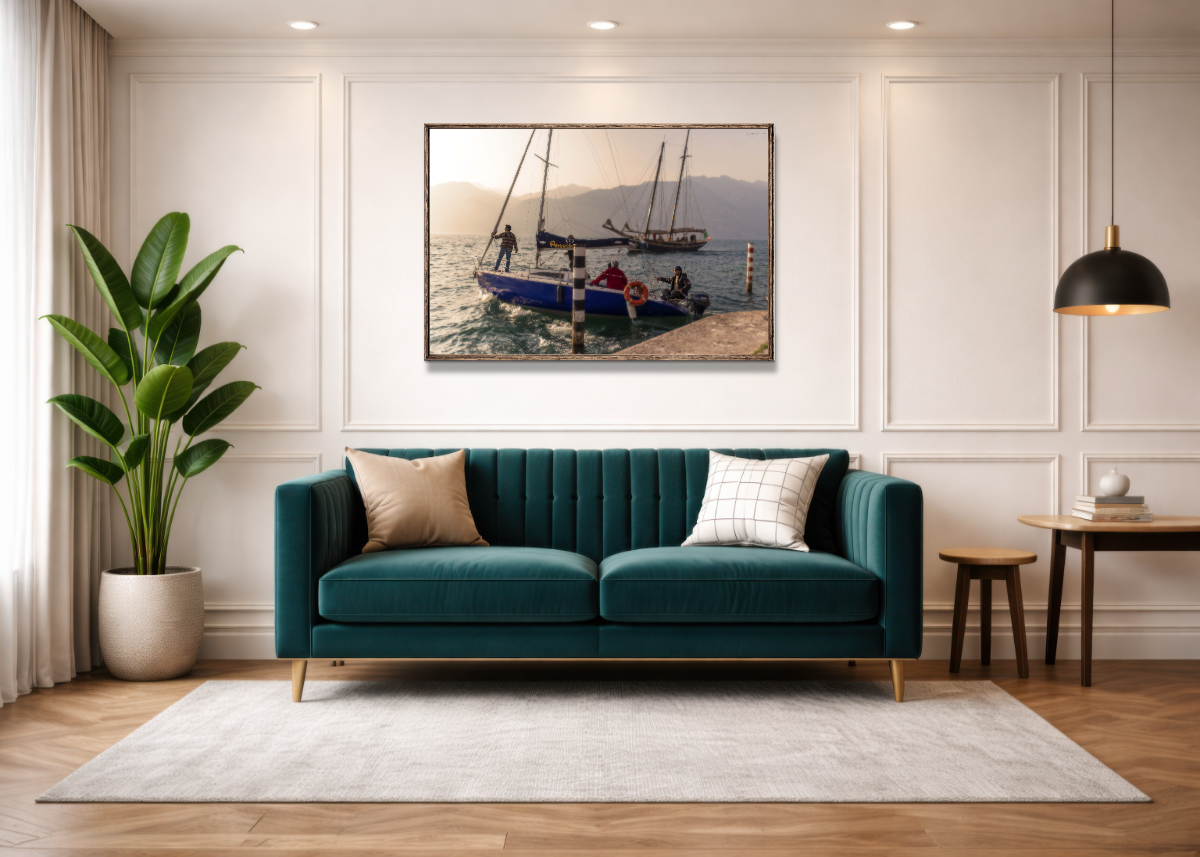 Living room with teal velvet sofa, beige and checkered pillows, large indoor plant in a white pot, framed nautical artwork, side tables, and black hanging lamp.