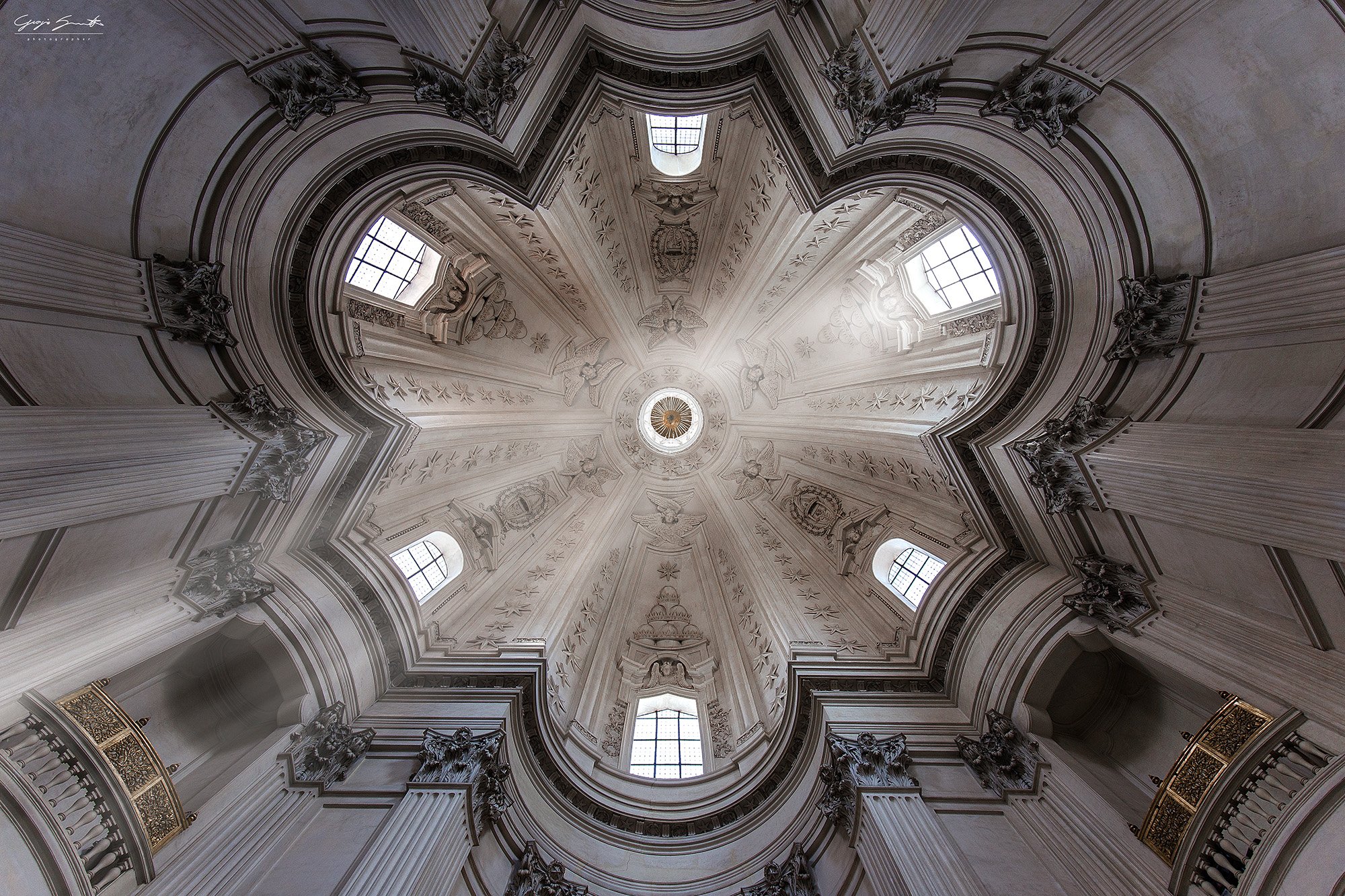 Borromini's star-shaped vault at Sant'Ivo alla Sapienza, Rome — black and white fine art photograph of Baroque ceiling with stucco reliefs and radial natural light.