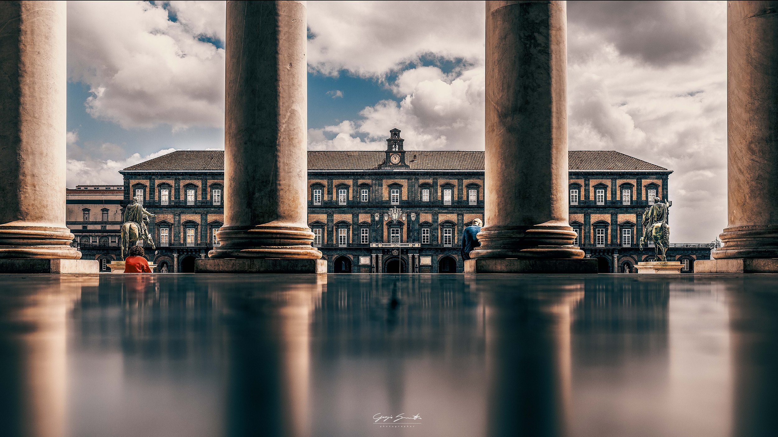 Palazzo Reale Naples viewed through stone columns with statues and street lamps — fine art architecture photography print by Hermes Gray, limited edition