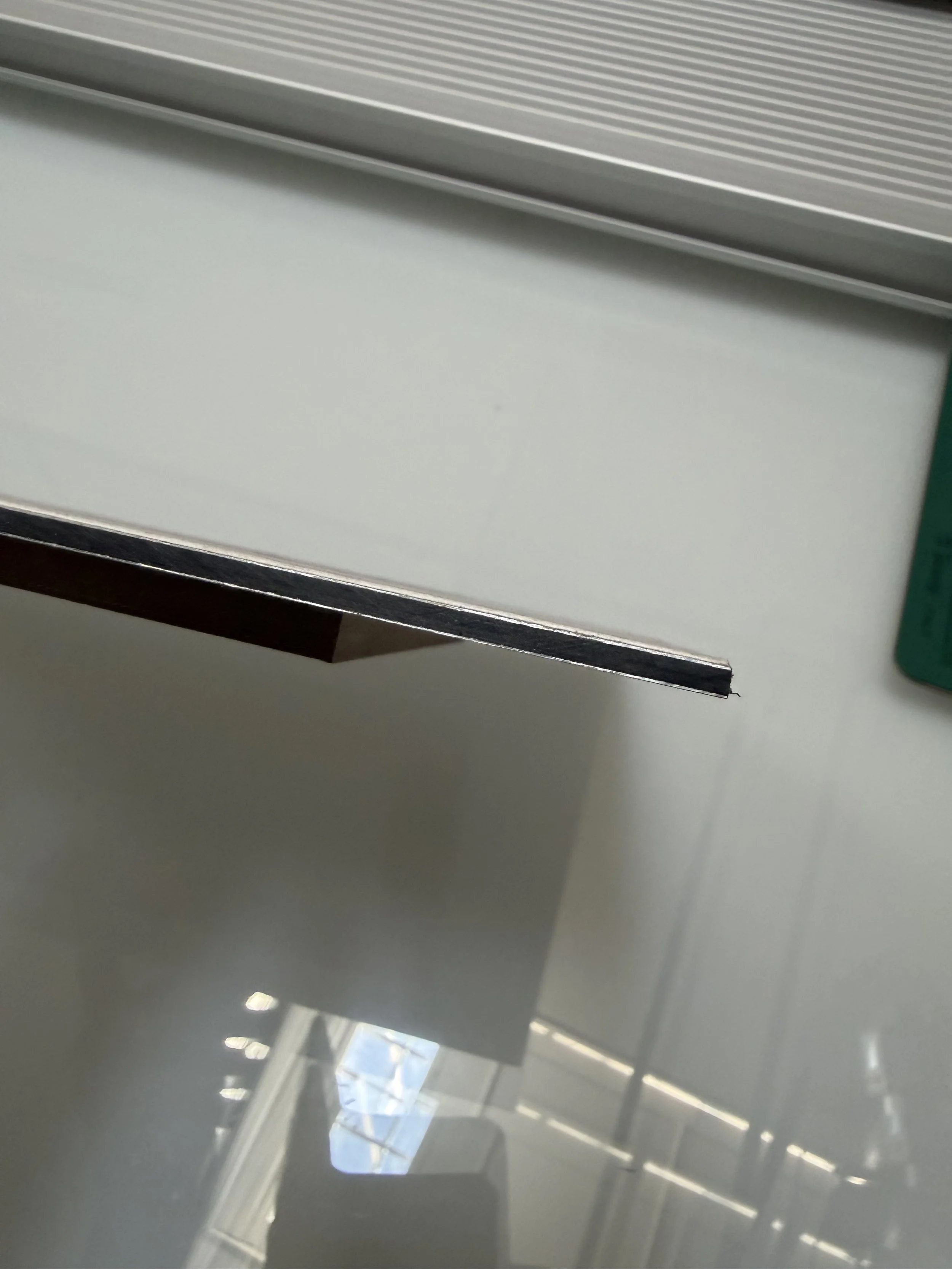 Cross-section of a Dibond aluminum composite panel used for fine art print mounting, showing the polyethylene core between two aluminum sheets — Hermès Gray frameless presentation.
