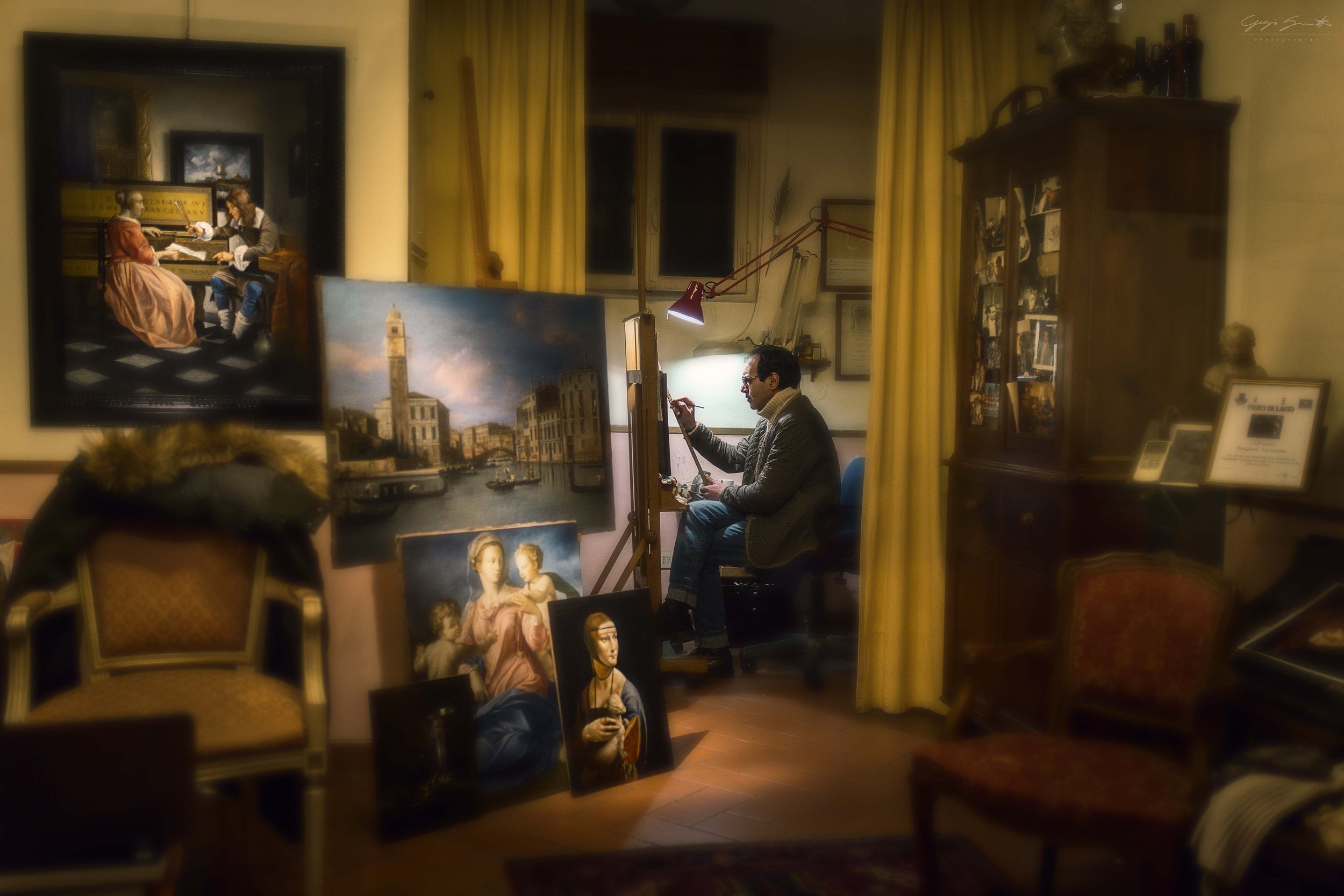 Artist painting portraits in a studio with red lamps and yellow curtains — fine art street photography print by Hermes Gray, limited edition