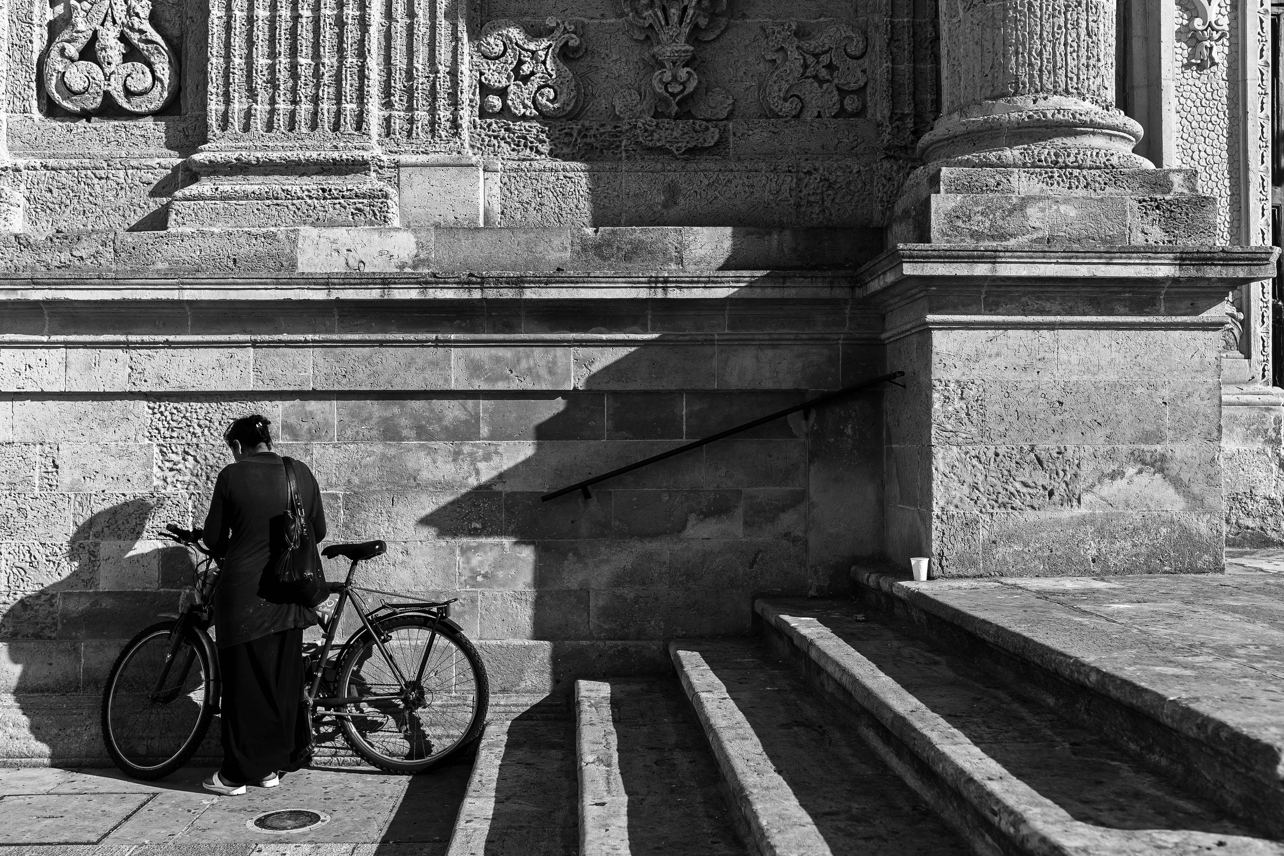 Cyclist resting beside historic building staircase — fine art street photography print by Hermes Gray, limited edition