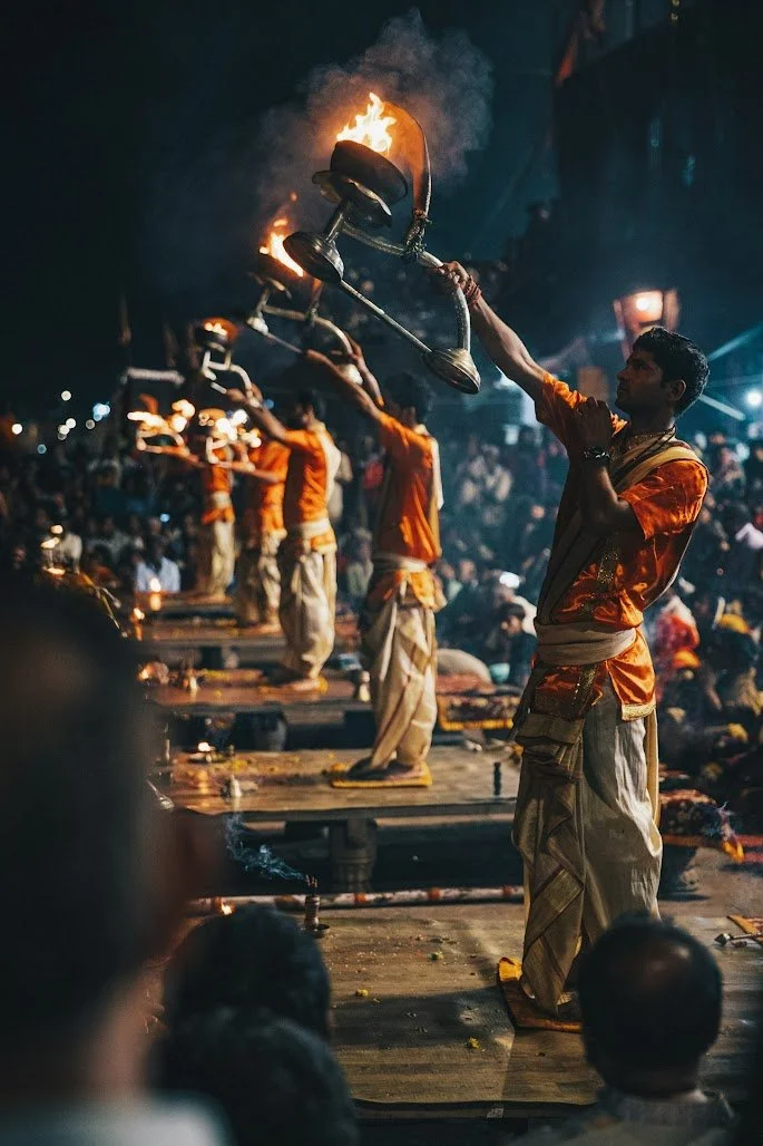 Men dressed in traditional Indian attire performing a ritual involving fire and pots during a cultural or religious ceremony at night, with an audience watching.