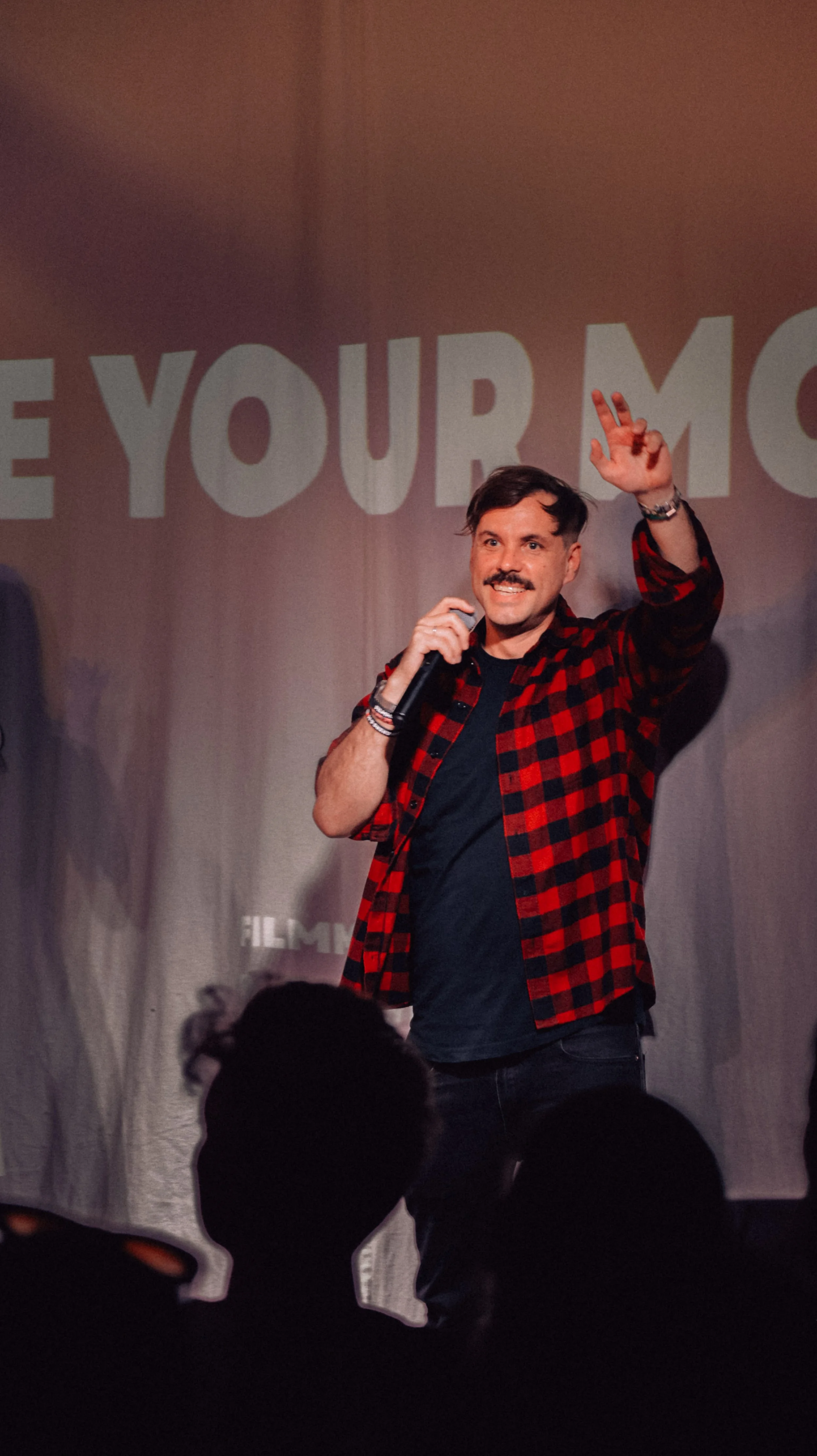 man with beard and jacket on stage talking