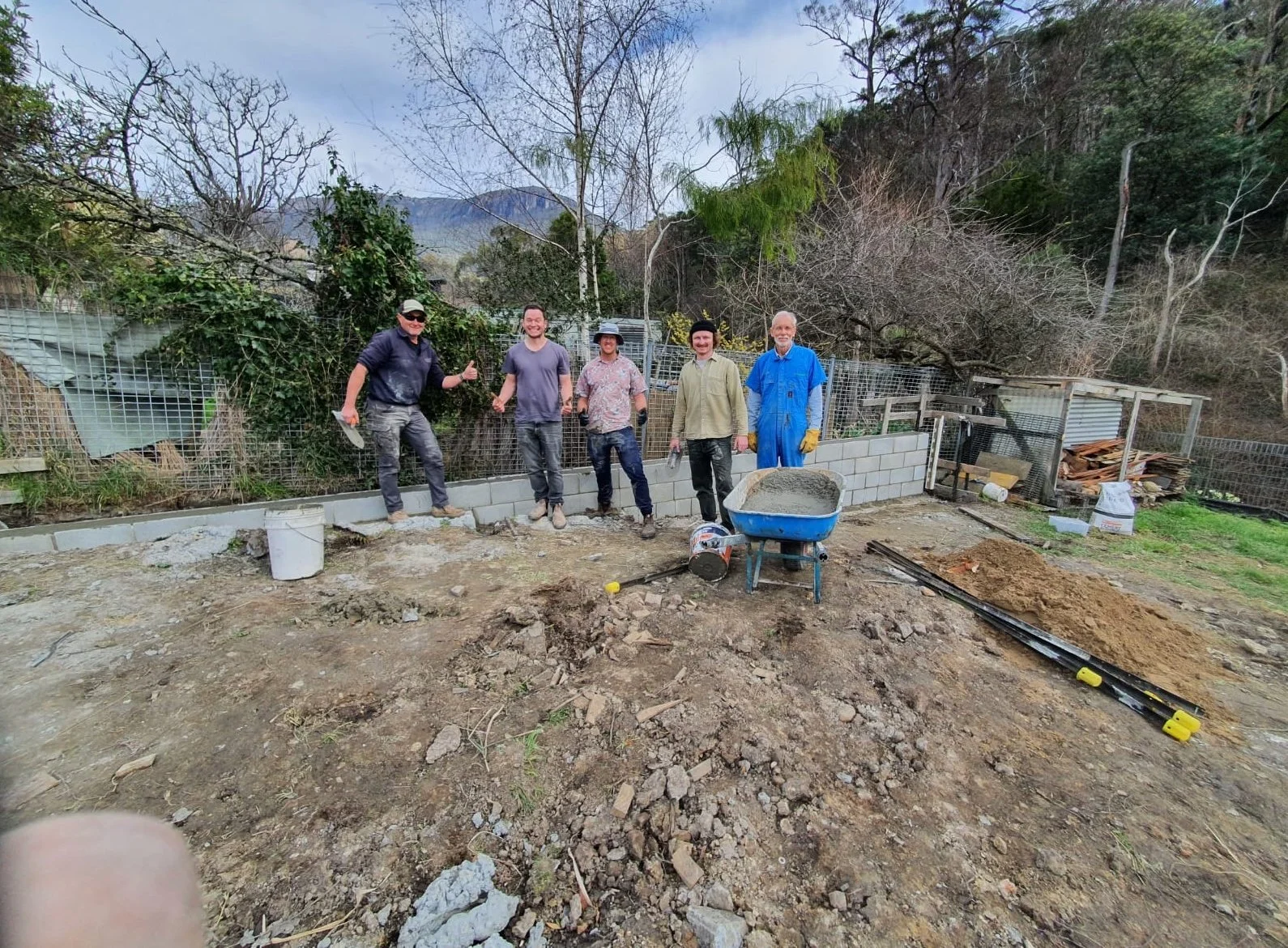 Students celebrating the completion of a concrete pour during a timber framing class at Ground Up Workshops