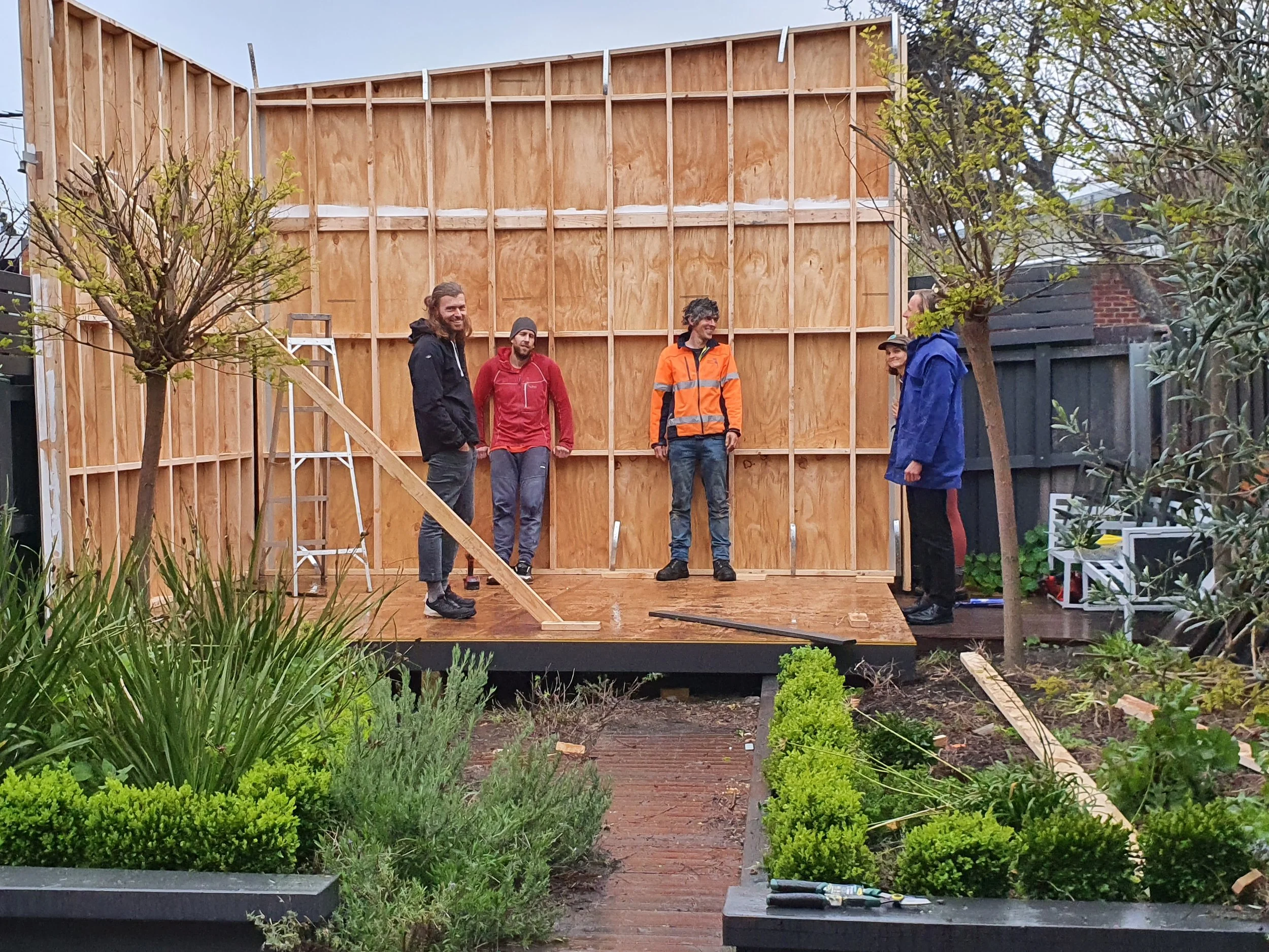 Students marking a major construction milestone at Ground Up Workshops after completing a full-height timber wall during a hands-on carpentry course.