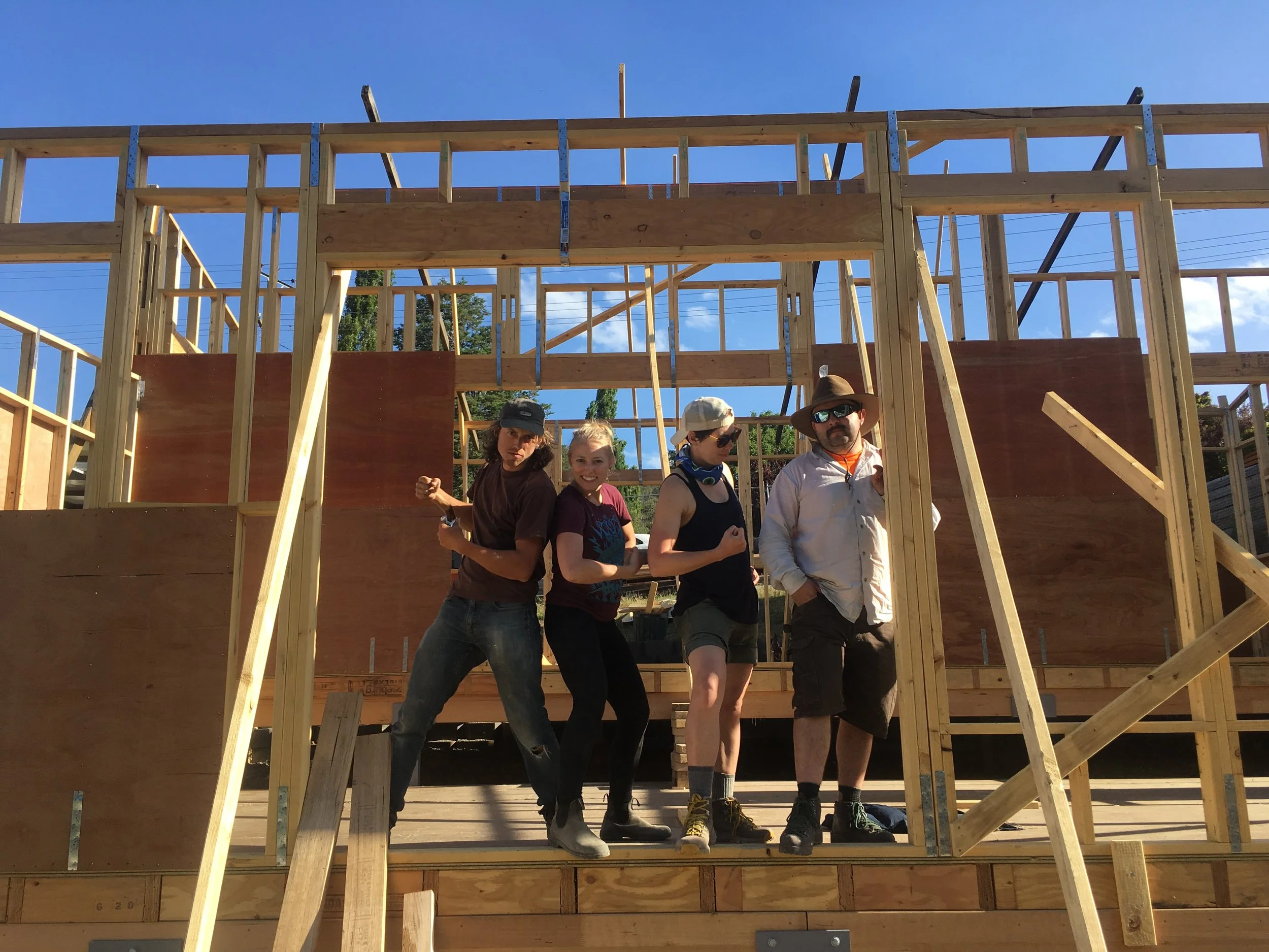Students celebrating their progress during a Ground Up timber framing course, learning practical carpentry skills while building a the walls timber shed.