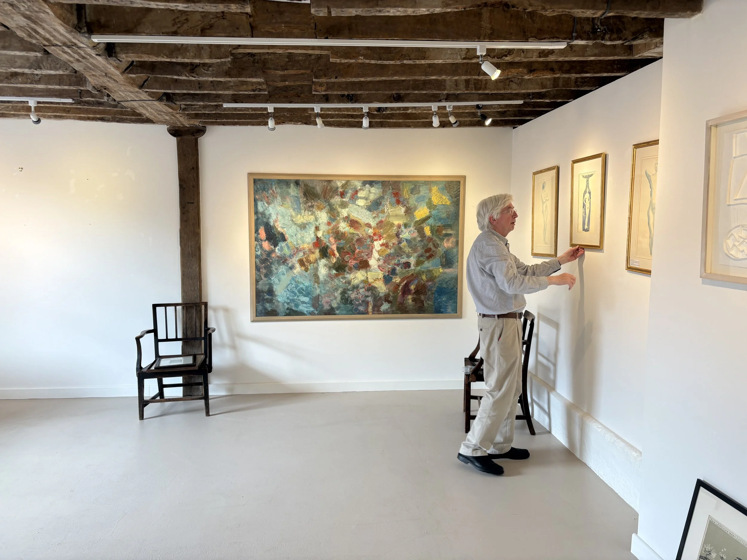 inside Katharine House Art Gallery Christopher Gange is adjusting the hanging of an artwork