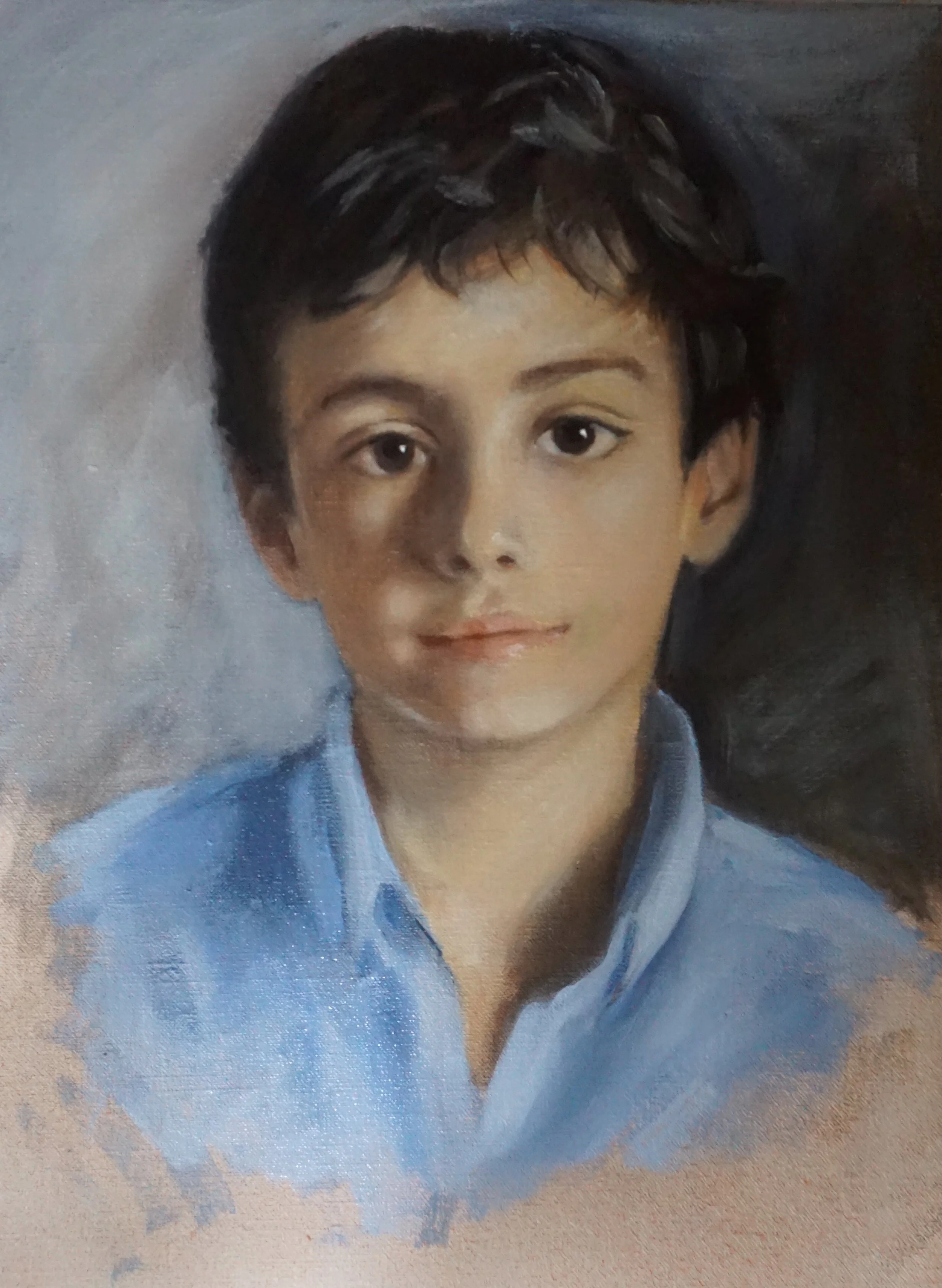 A portrait of a young woman with short black hair and a blue shirt. The background appears to be a neutral, subdued tone.