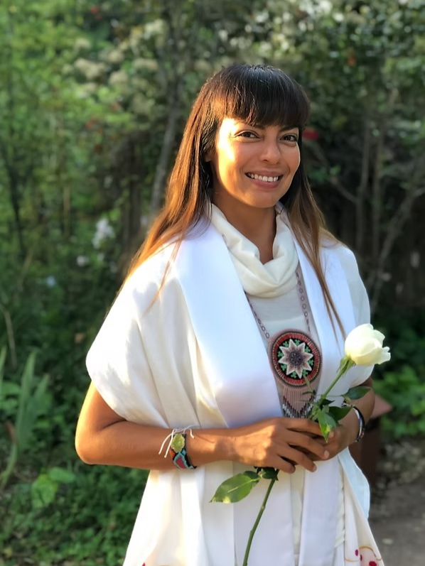 Adriana Gonzalez Villa, retreat facilitator, standing outdoors and holding a white rose