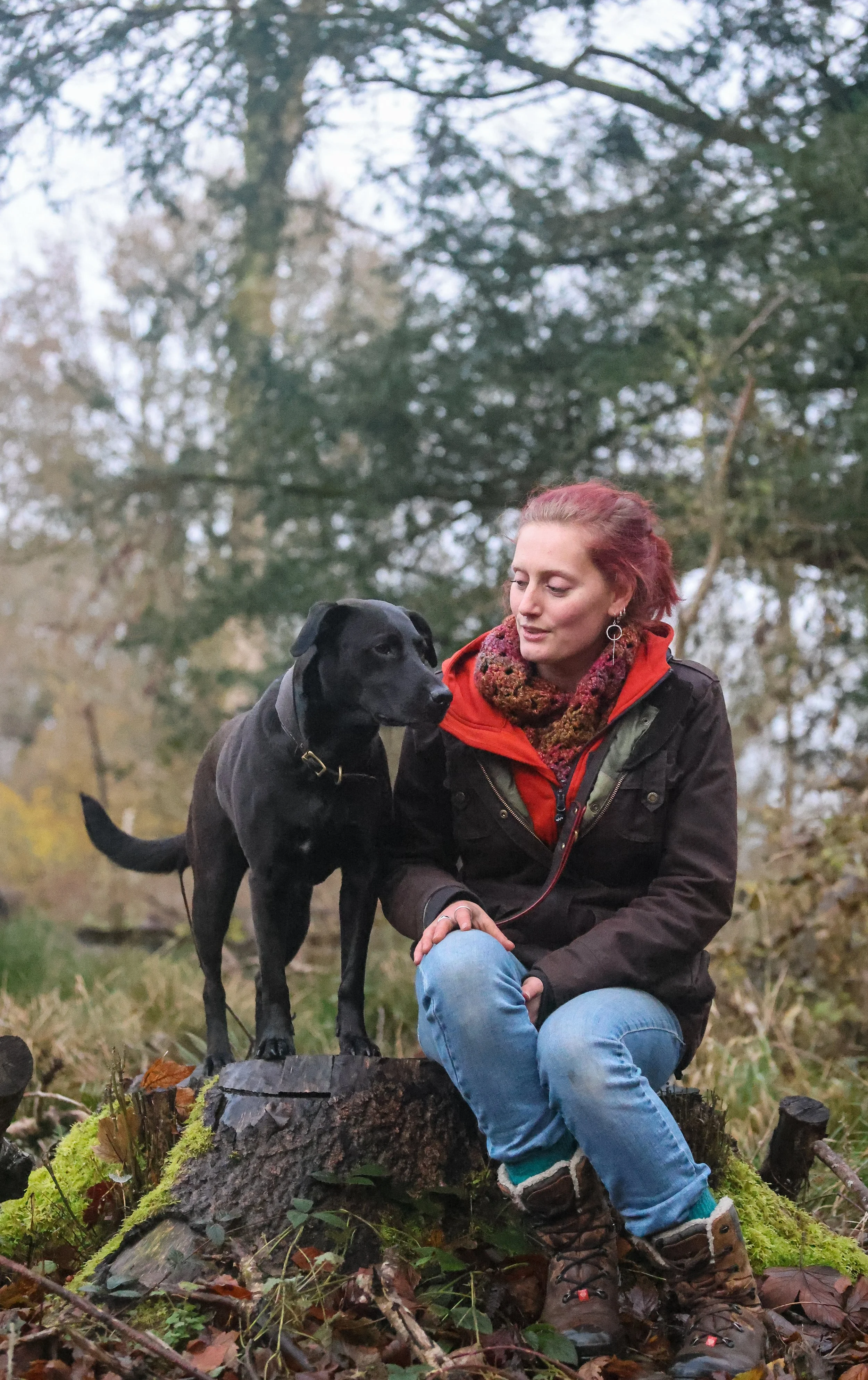 female dog trainer in dorset sat with her dog on a tree stump