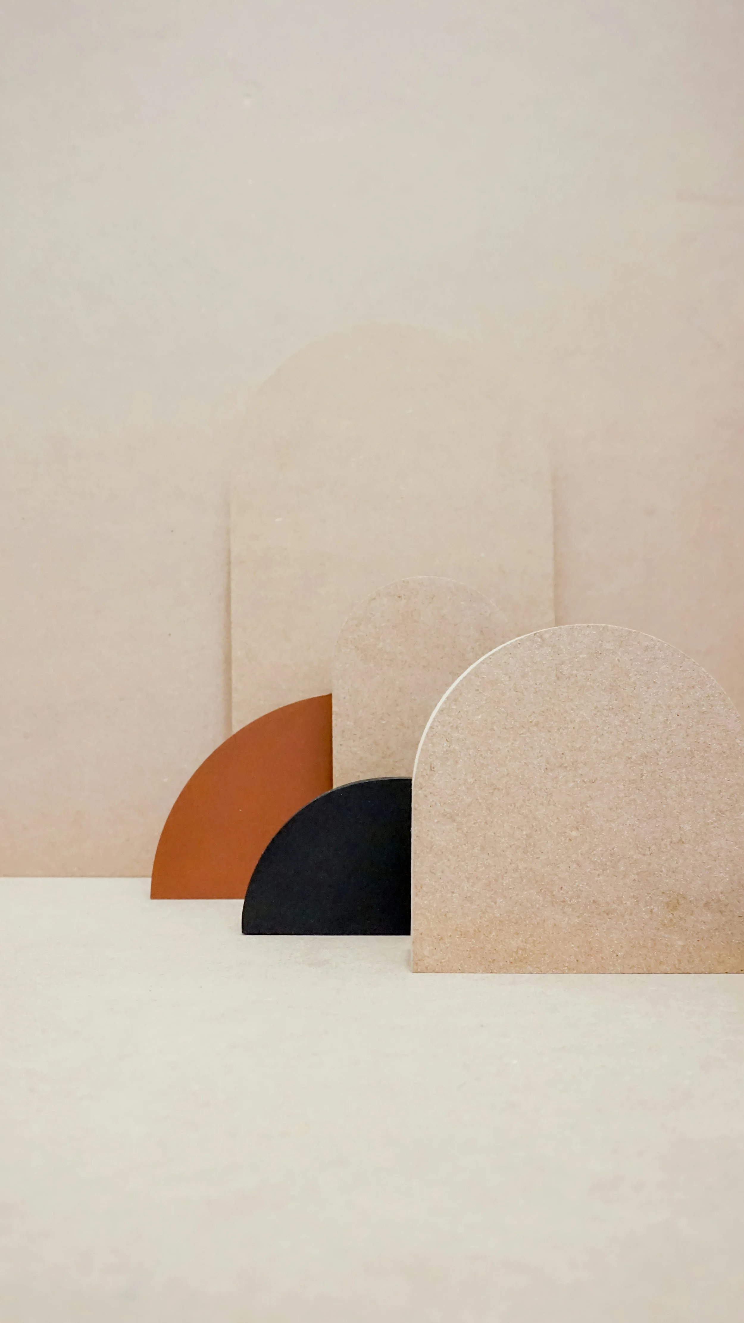 Abstract geometric shapes including semicircles in orange, black, beige, and cream colors against a beige background.