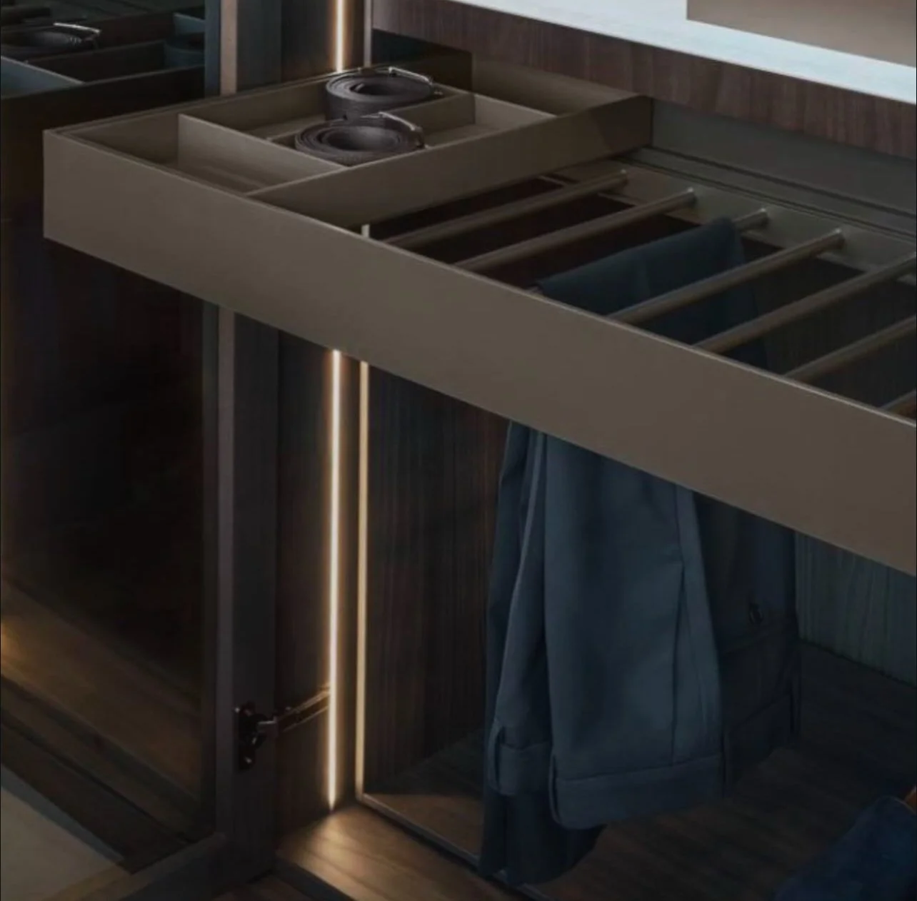 A modern wooden bar or counter with integrated open storage compartments and a removable panel. A blue jacket is hung on the side of the counter, and dark-colored speakers are placed on top.