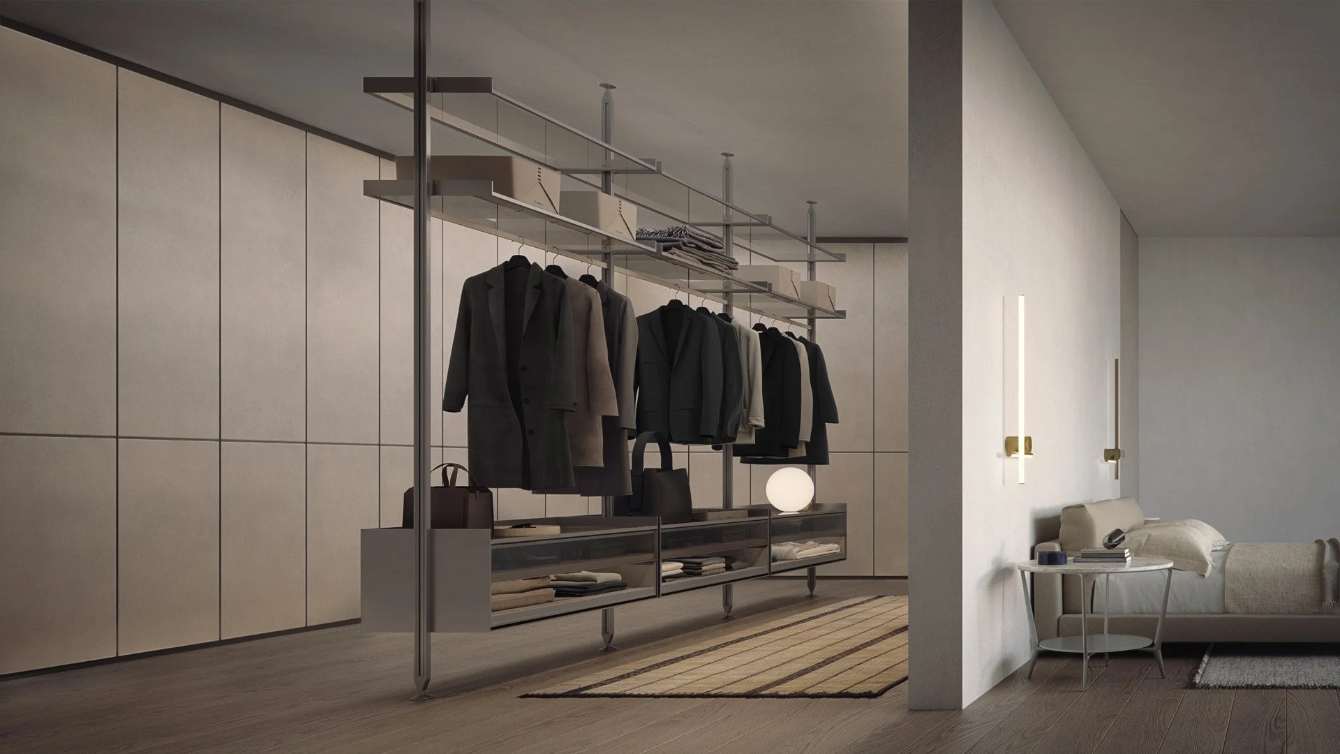 Modern interior living space with a bedroom area separated by a partial wall, featuring a minimalist sofa, side table, and wall-mounted lights. Adjacent open closet with hanging coats, boxes, and folded clothes, illuminated by ambient lighting.