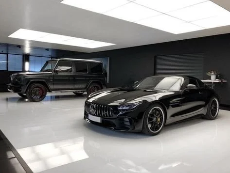 Two luxury cars, a black SUV and a black sports car, displayed in a modern indoor showroom.