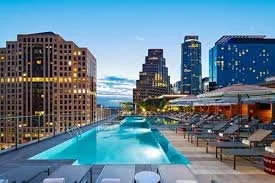 Rooftop swimming pool overlooking city skyline with tall buildings and clear sky