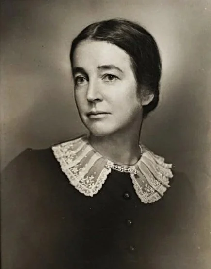 Black and white portrait of a woman with dark hair, wearing a dark dress with a lace collar.