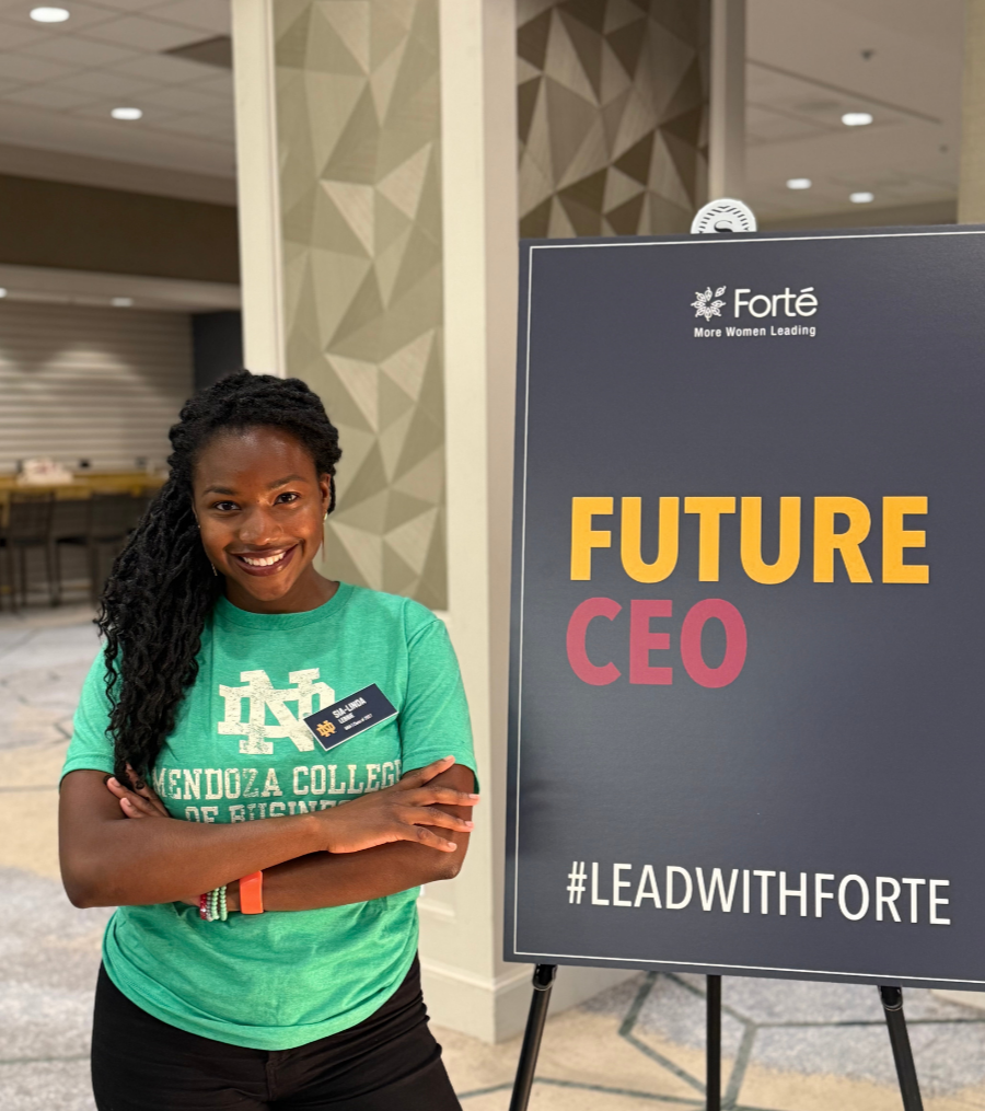 LEAD for Education student standing with her arms crossed and smiling next to a sign that reads 'Future CEO' with a hashtag #LeadWithForte, in an indoor setting with geometric wall patterns.