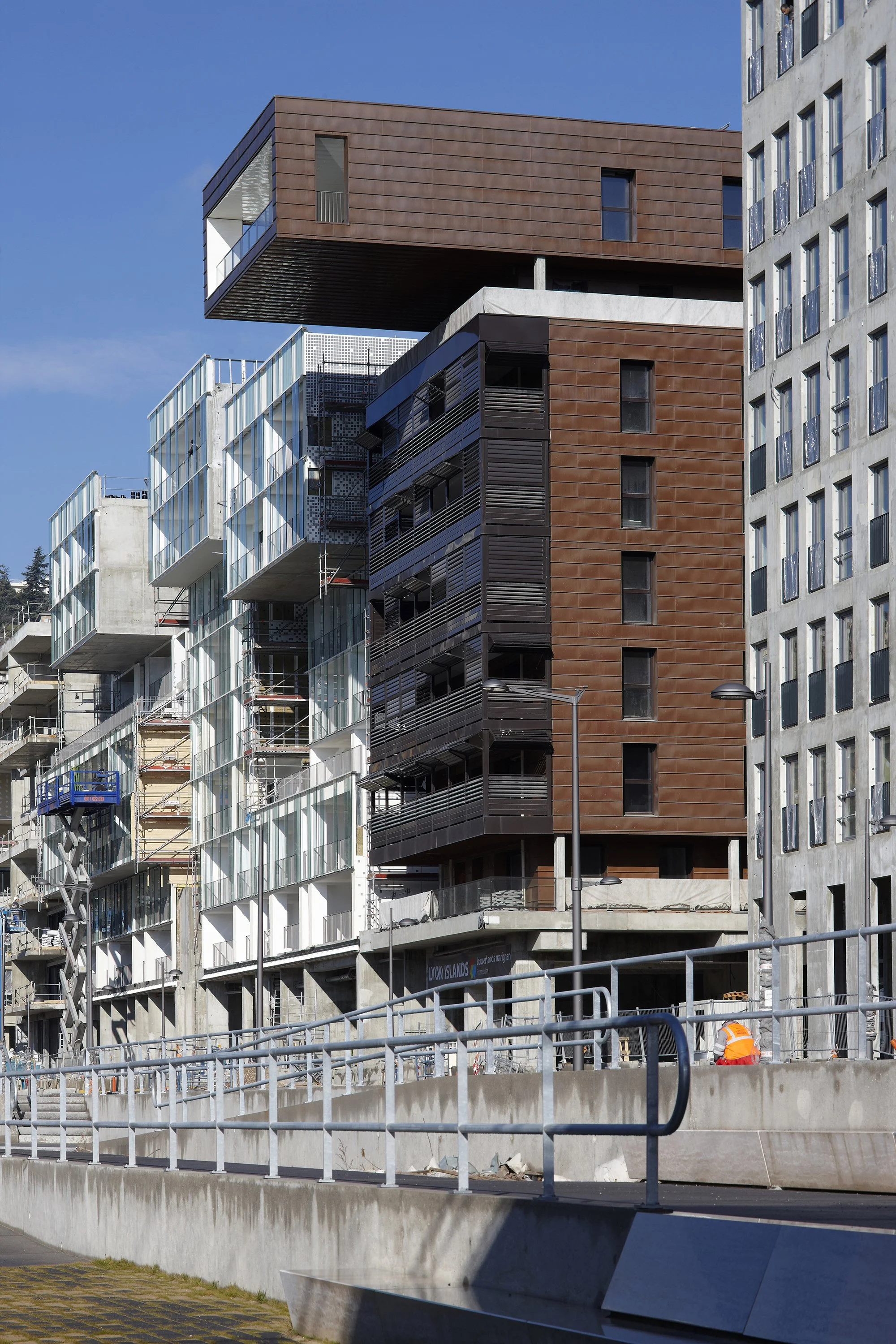 Construction de bâtiments modernes avec plusieurs étages, échafaudages et travailleurs sur le site.