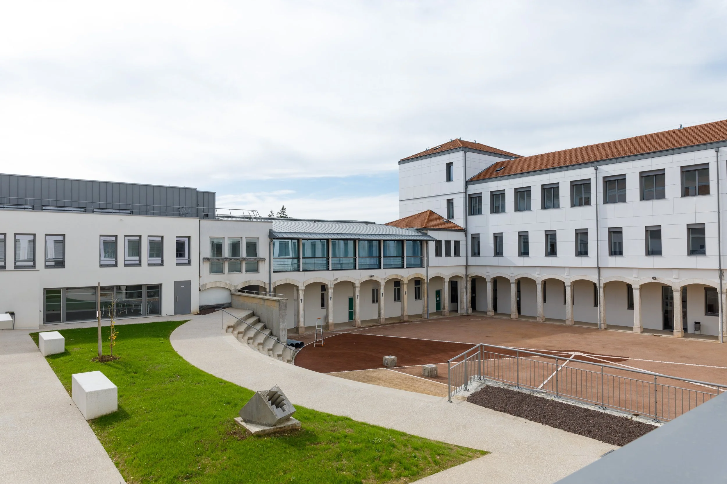 Vue d'une cour intérieure d'un bâtiment moderne avec un espace de jeux et des espaces verts.