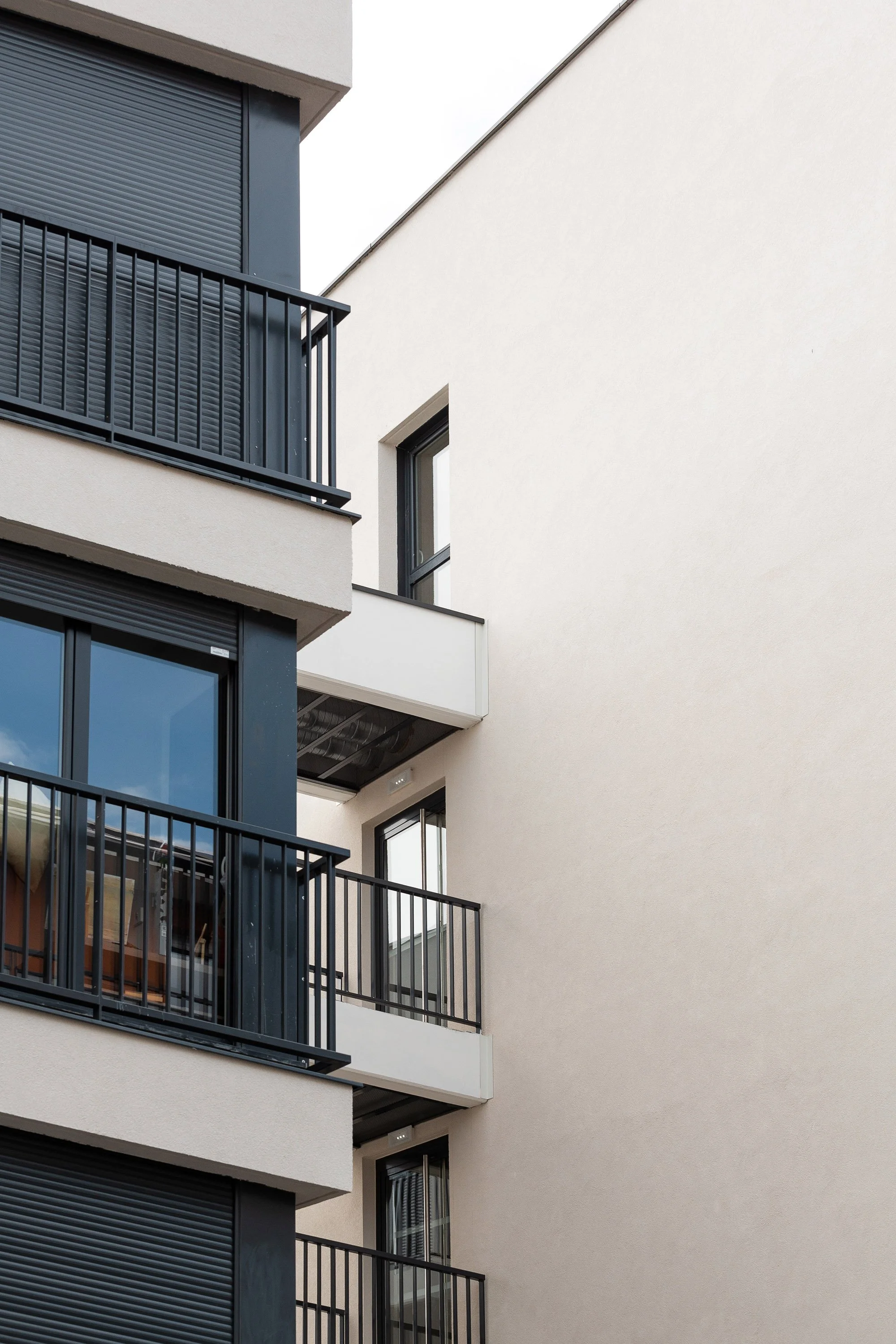 Bâtiment résidentiel moderne avec des balcons en métal noir et des fenêtres avec volets roulants