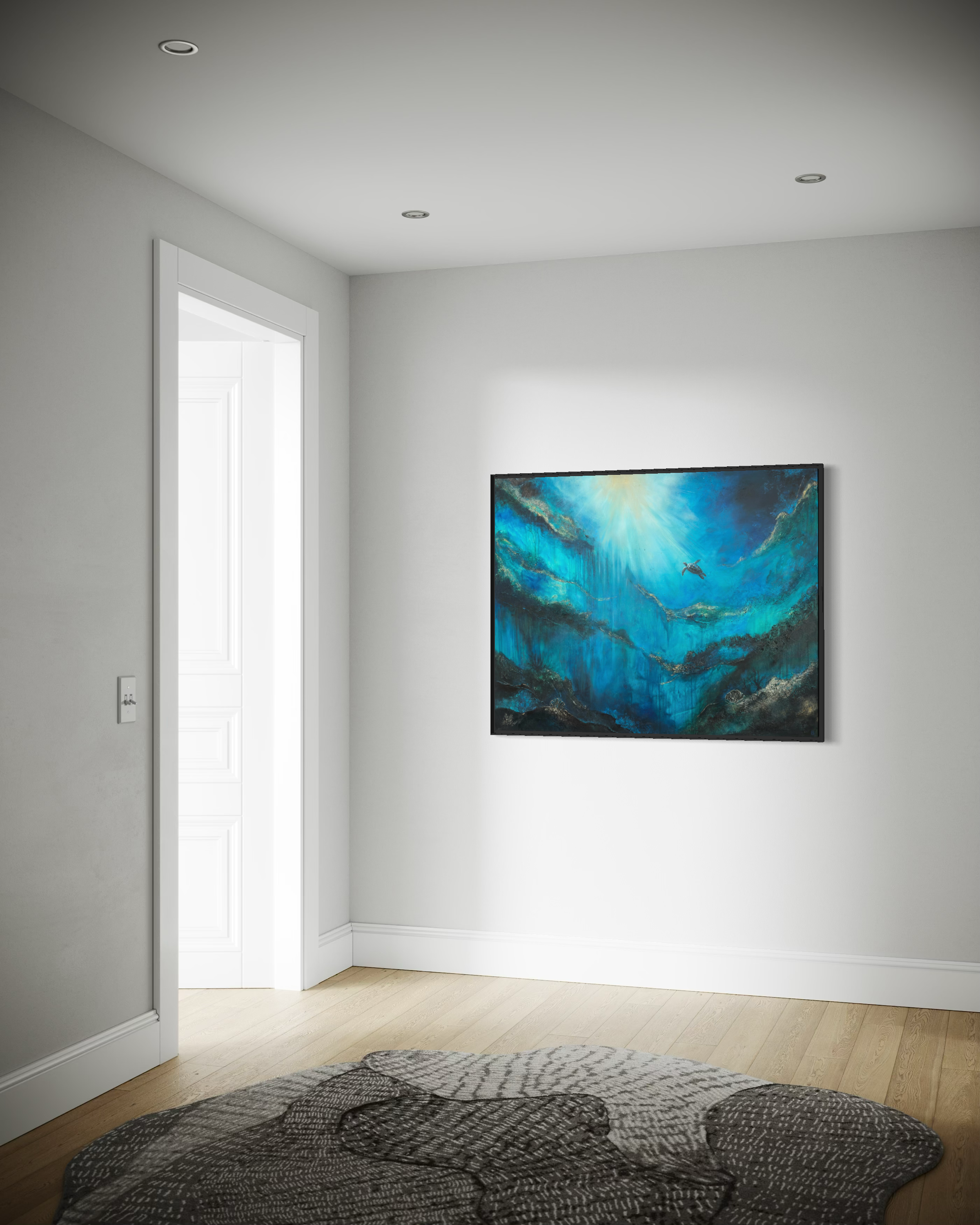 A corner of a minimalist living room with a light gray painted wall, a white door open to another room, a flat screen television mounted on the wall showing colorful abstract art, a patterned area rug on the wooden floor, and part of a sofa with a dark patterned cushion in the foreground.