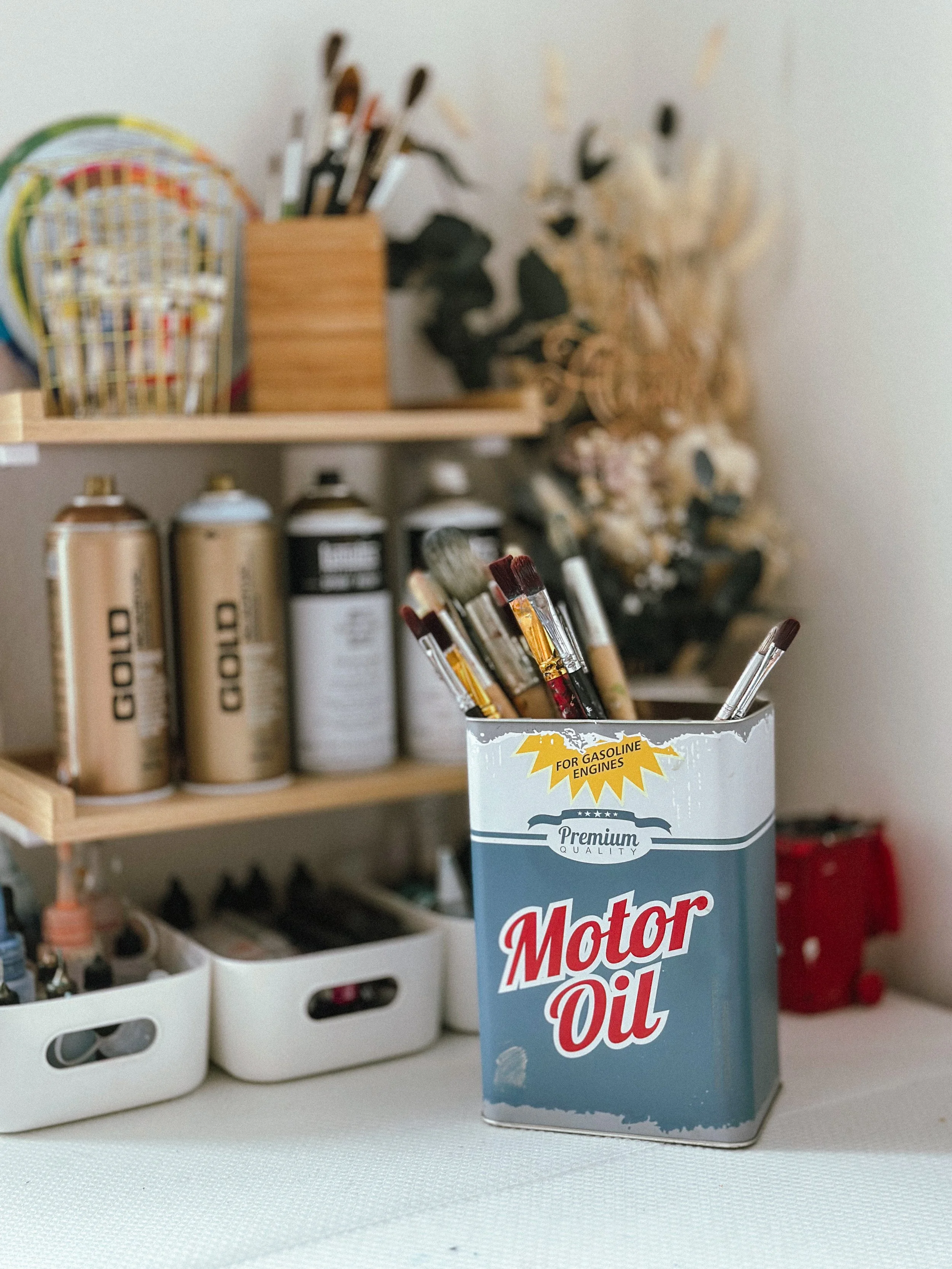 A blue rectangular container with red and white text reading 'Motor Oil' and a faded yellow starburst graphic that says 'For Gasoline Engines' on a white surface.