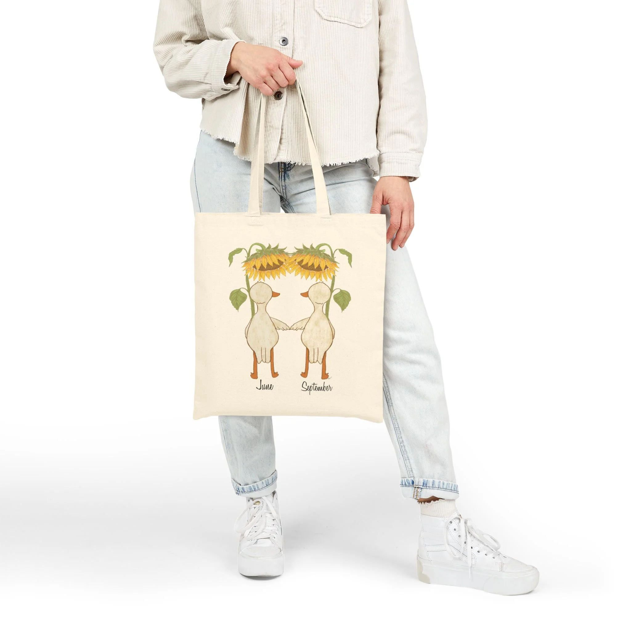 Hand holding Cotton Tote Bag featuring hand illustrated ducks or geese with large sunflowers as umbrellas available for personalization