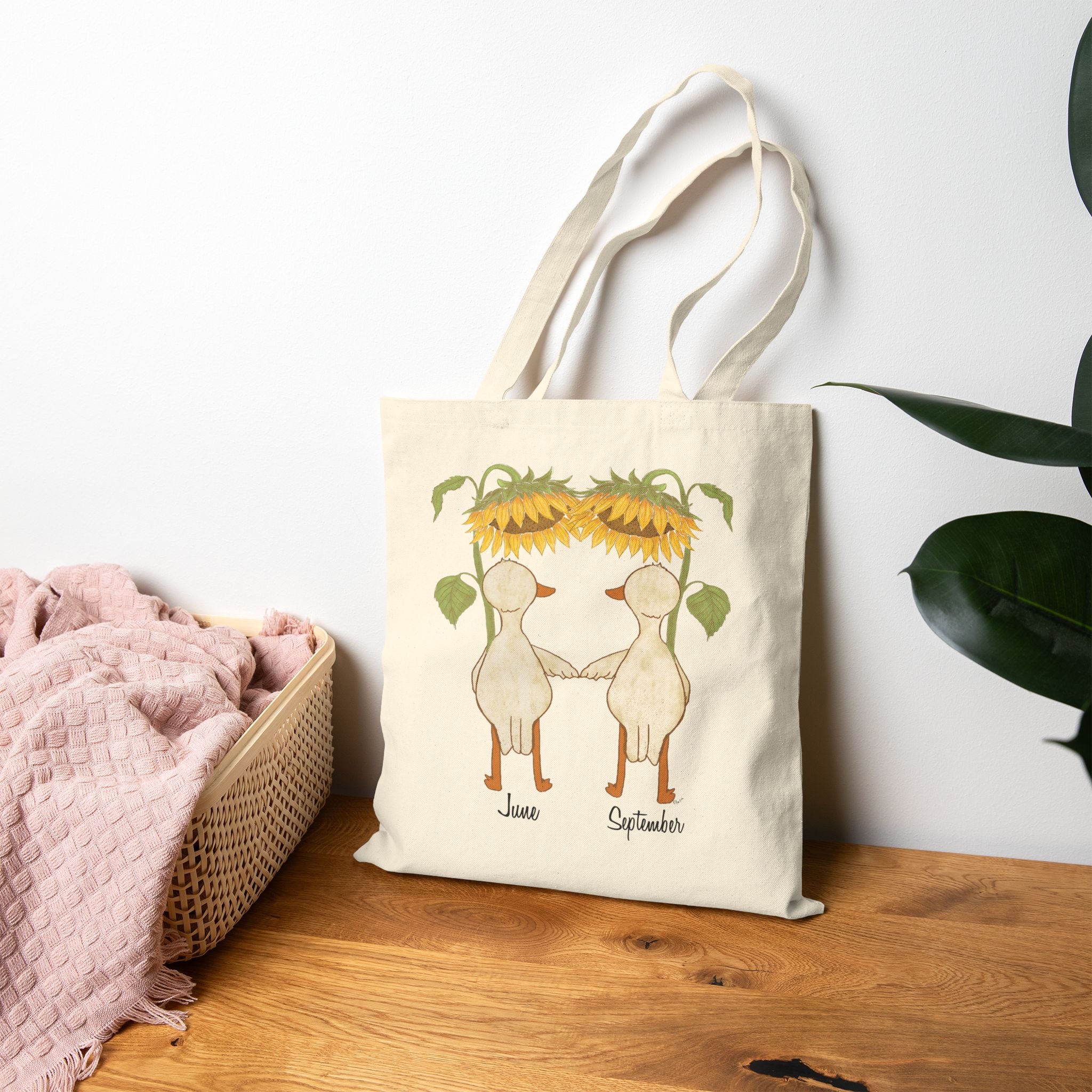 Cotton Tote Bag sitting on floor featuring hand illustrated ducks or geese with large sunflowers as umbrellas available for personalization