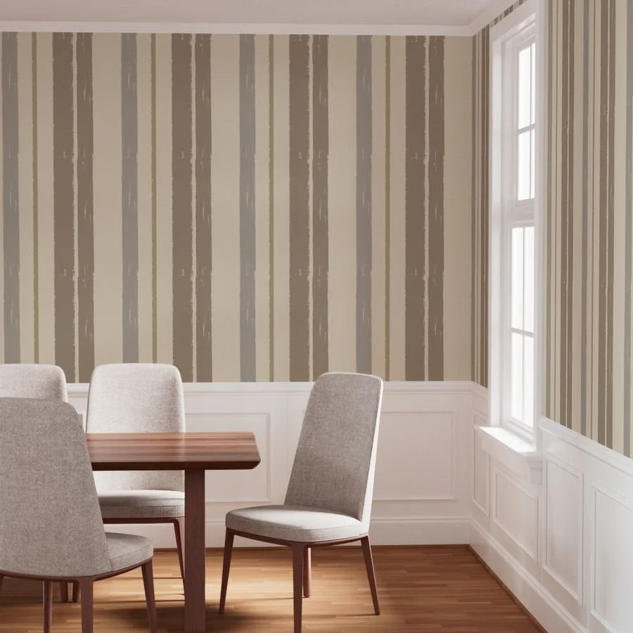 Empty dining room with striped beige and green wallpaper, white wainscoting, a wooden table, beige upholstered chairs, and a large window letting in natural light.