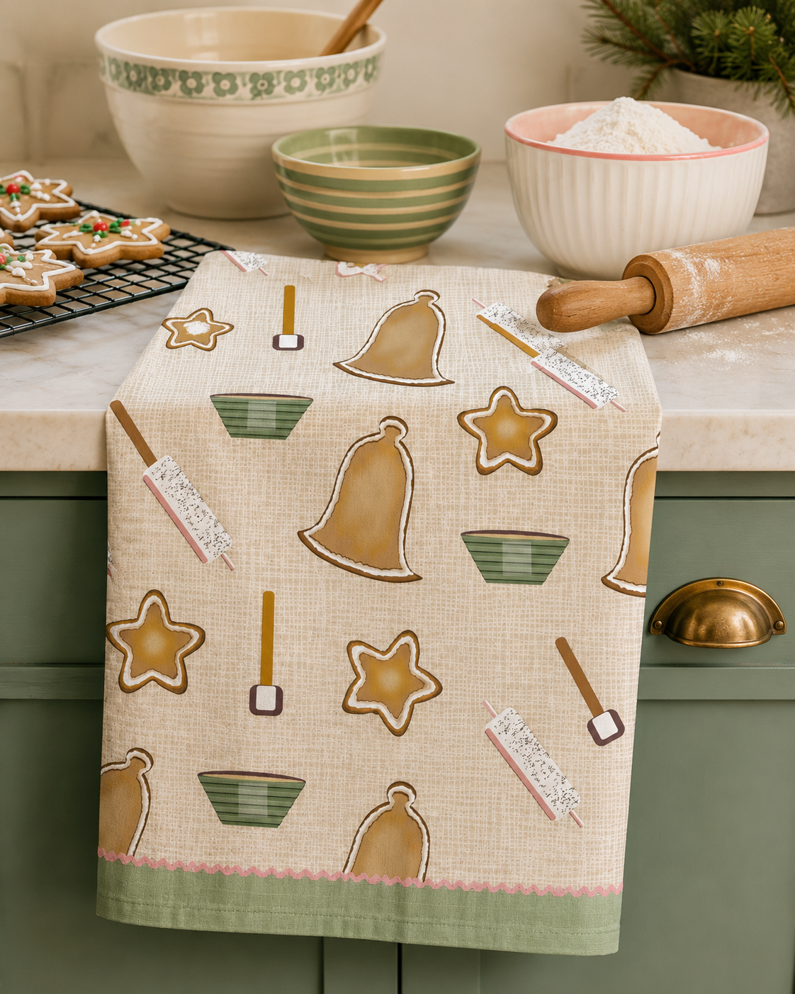 A Christmas Tea Towel with a festive design of bell and stars gingerbread cookies, with bowls, rolling pin and spatulas for baking.  A fun and festive tea towel for the holidays.