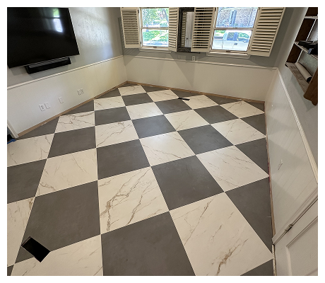 Empty room with black and white checkered tile floor, windows with shutters, and a wall-mounted TV.
