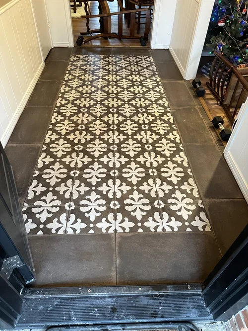 Tile foyer floor with patterned white and dark gray tiles, decorated for Christmas with a Christmas tree in the corner.