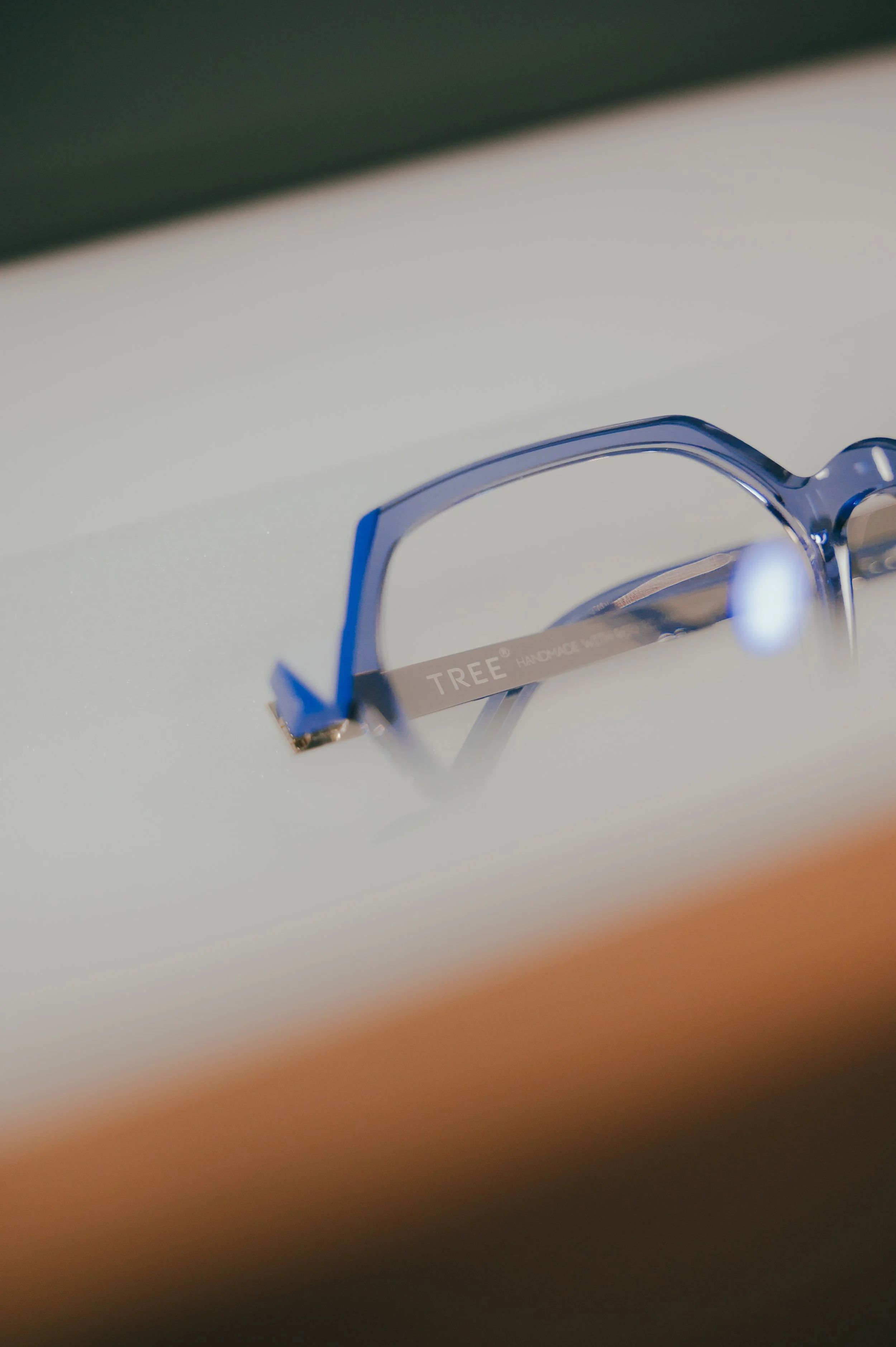 Close-up of a pair of blue eyeglasses resting on a white surface.