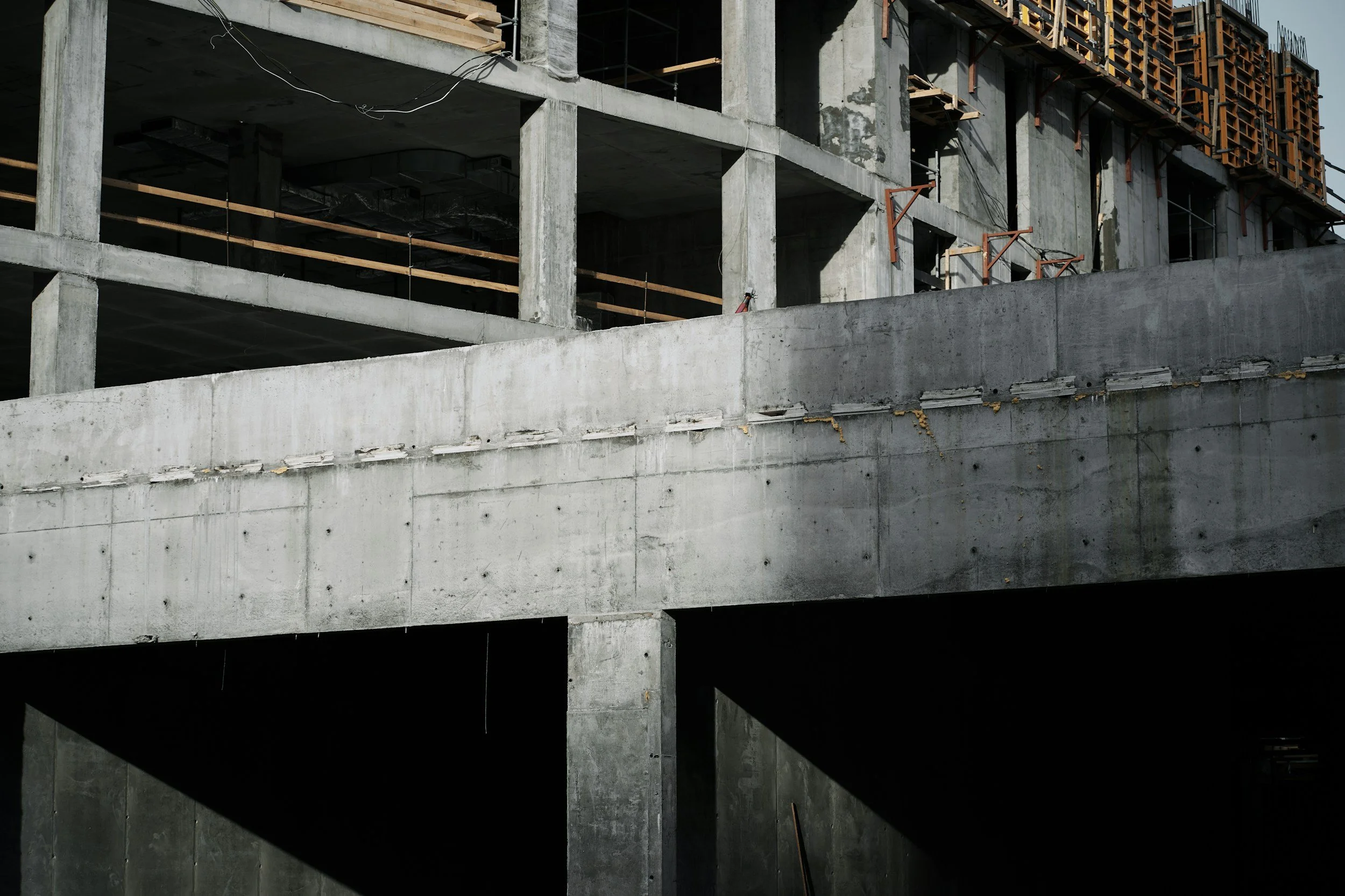 Construction site with unfinished concrete buildings under construction, showing exposed concrete walls, beams, and support structures.