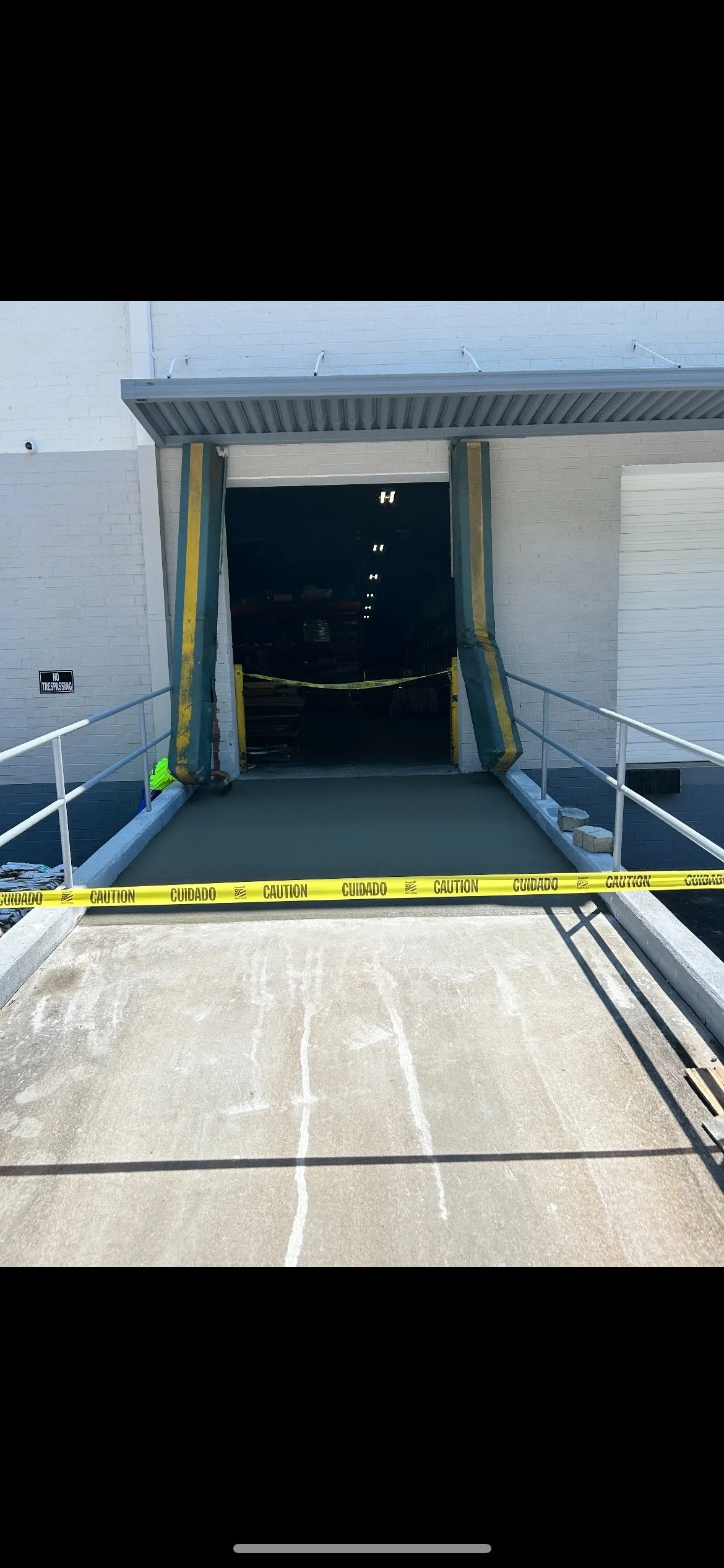 Loading dock entrance with caution tape and safety barriers, leading into a warehouse or storage area.
